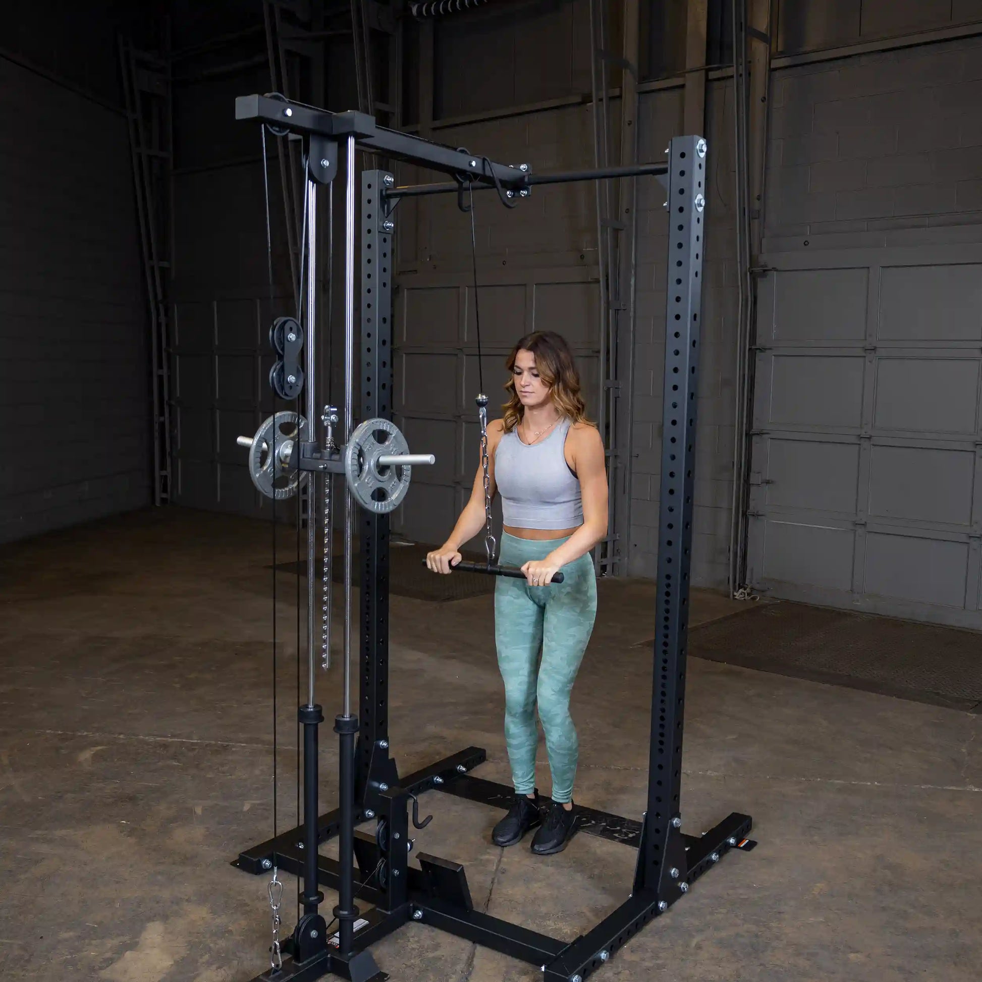 A woman performing an exercise using the Body-Solid Pro ClubLine Lat Attachment SPRHLA in a gym setting, featuring a cable machine with weights.