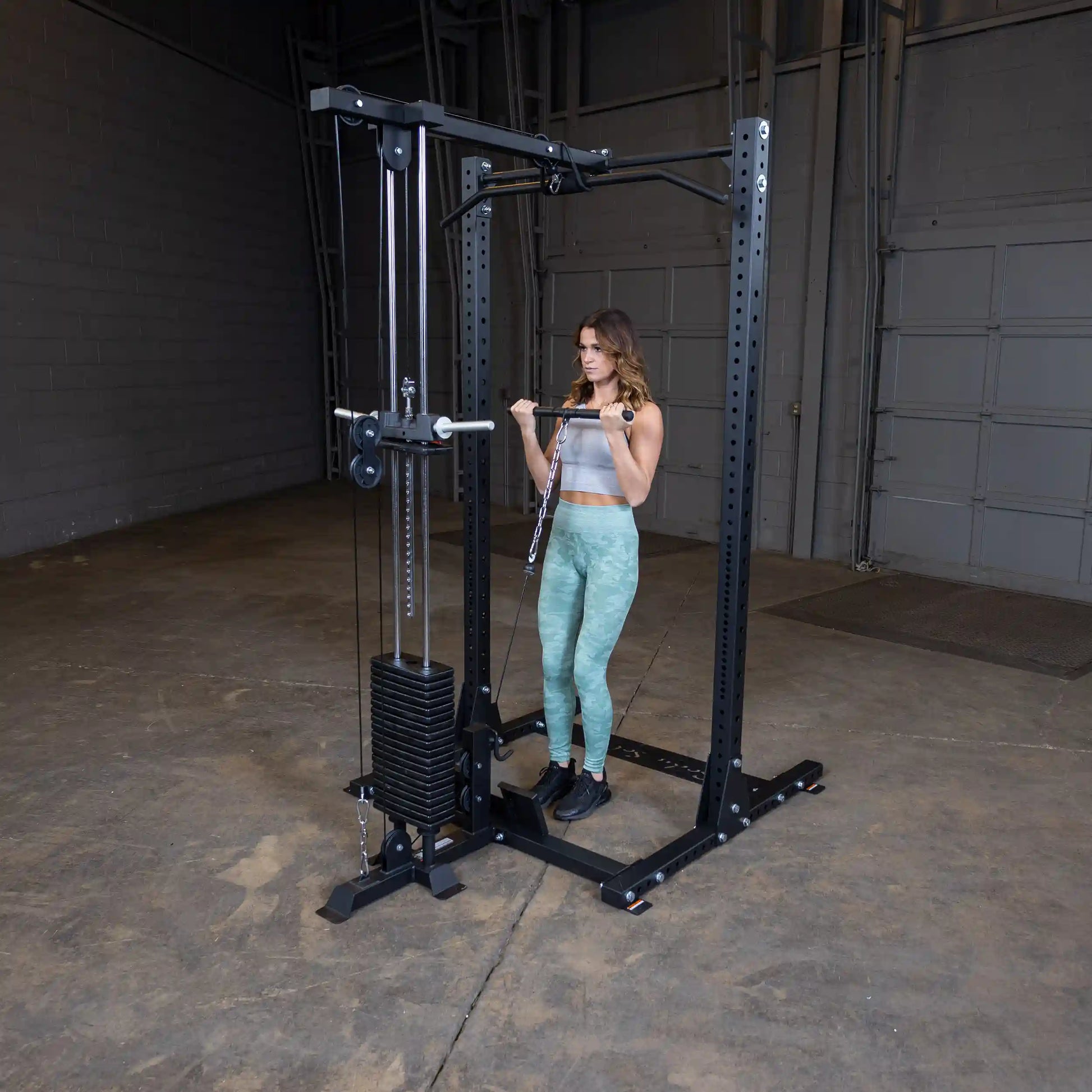 A woman using the Body-Solid Pro ClubLine Lat Attachment SPRHLA for strength training in a spacious gym setting.