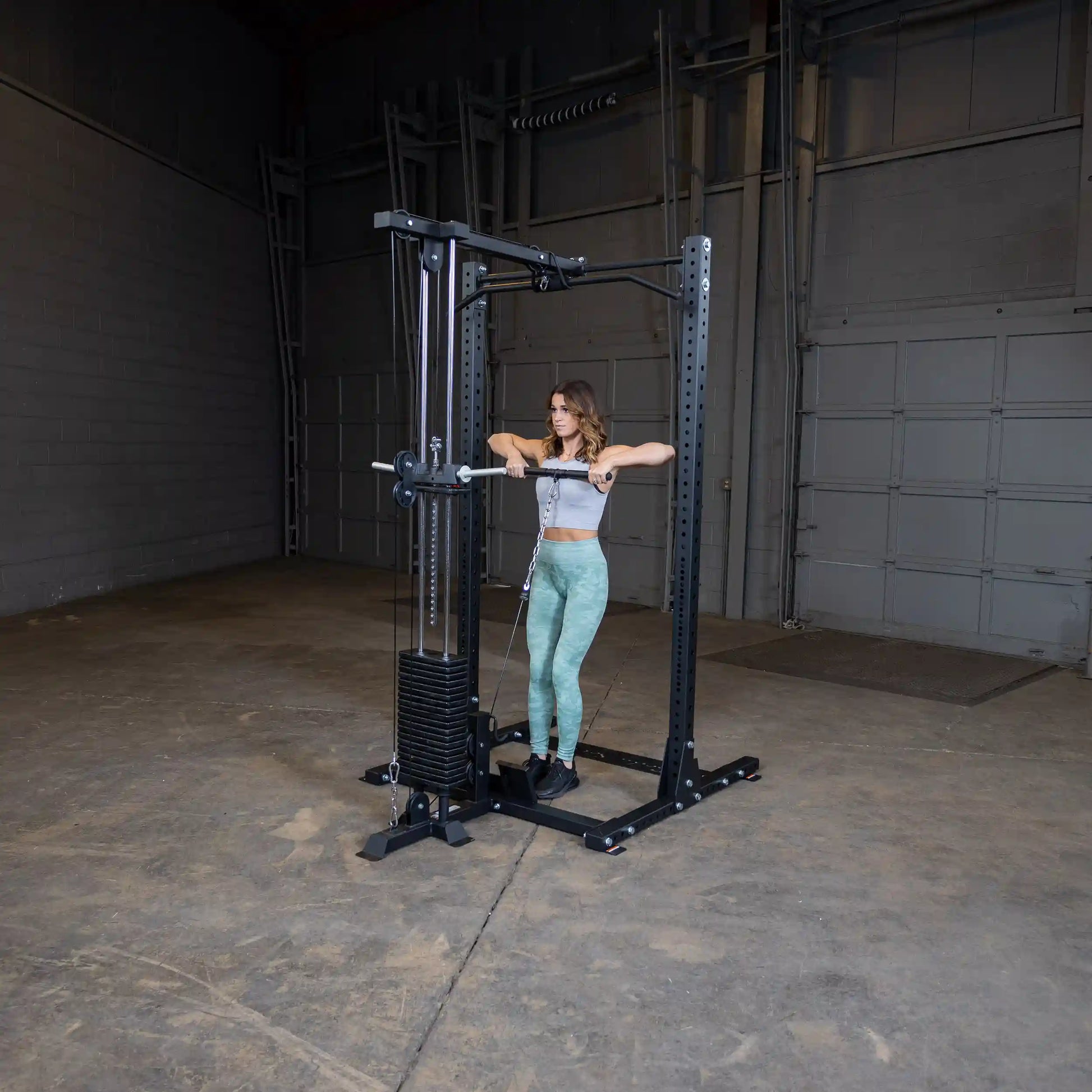 A woman using the Body-Solid Pro ClubLine Lat Attachment SPRHLA in a gym setting, performing a lat pulldown exercise.