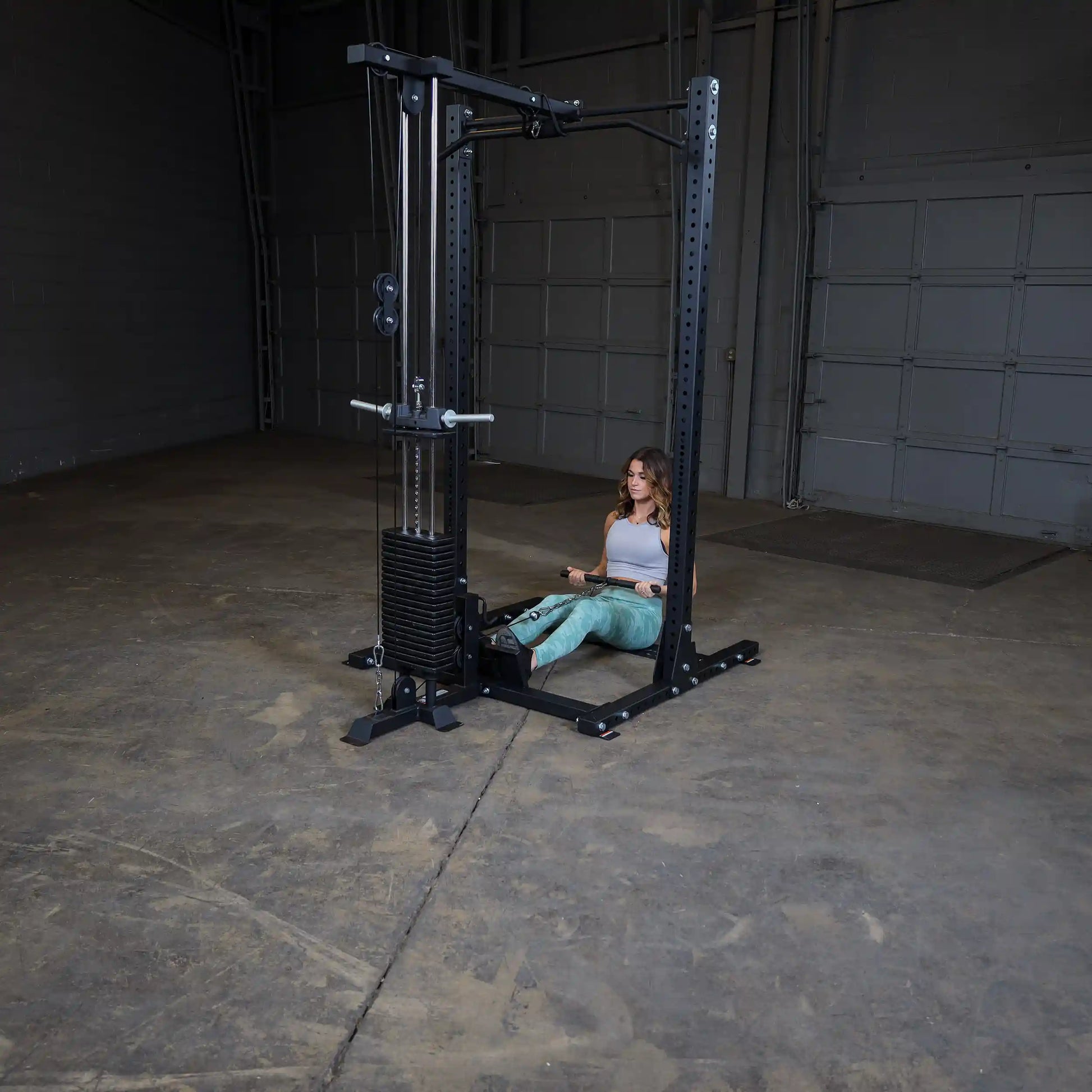 A woman performing seated rows on a Body-Solid Pro ClubLine Lat Attachment SPRHLA in a spacious gym environment.