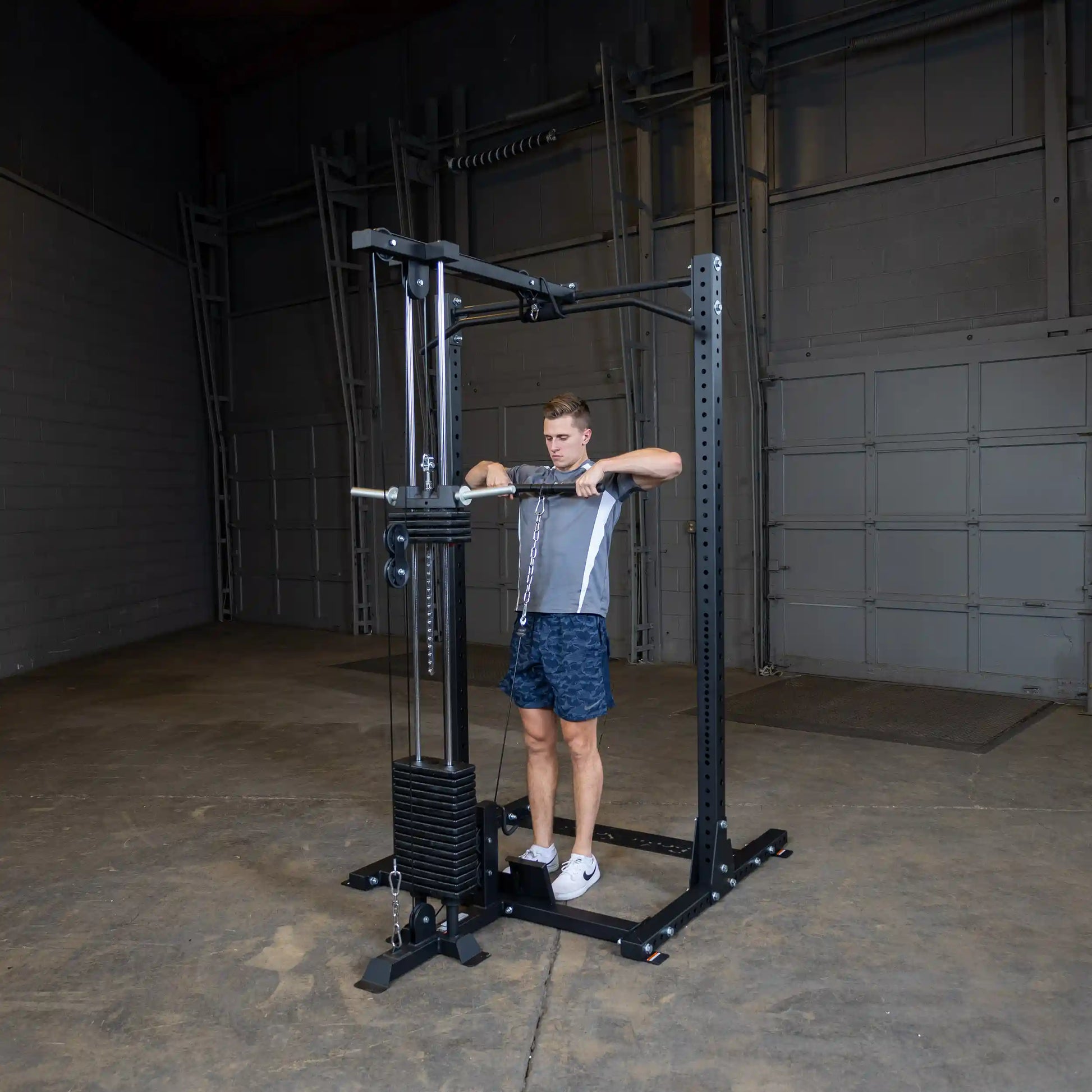 A person using the Body-Solid Pro ClubLine Lat Attachment SPRHLA in a spacious gym setting, performing a lat pulldown exercise.