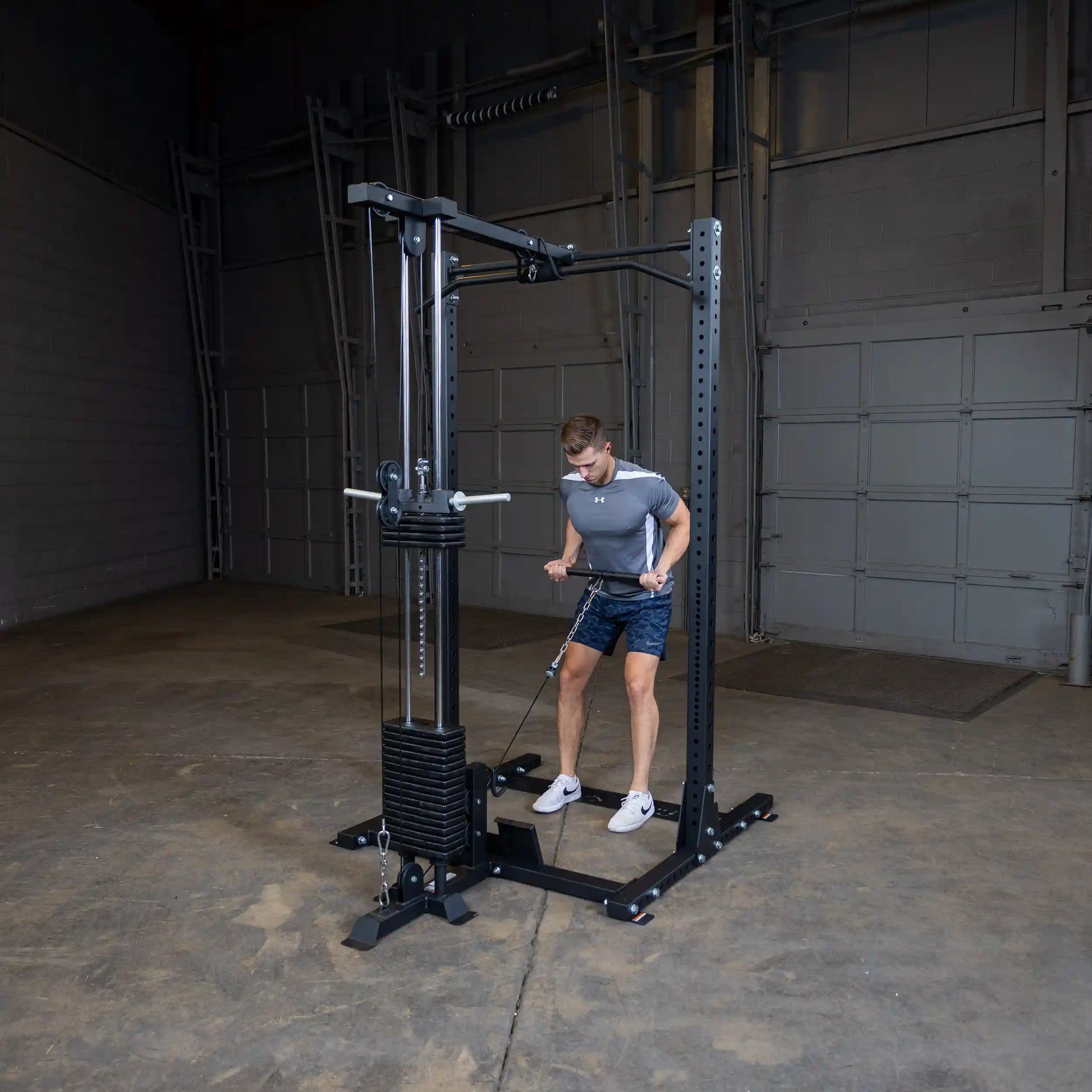 A person using the Body-Solid Pro ClubLine Lat Attachment SPRHLA in a gym setting, performing a lat pull-down exercise.
