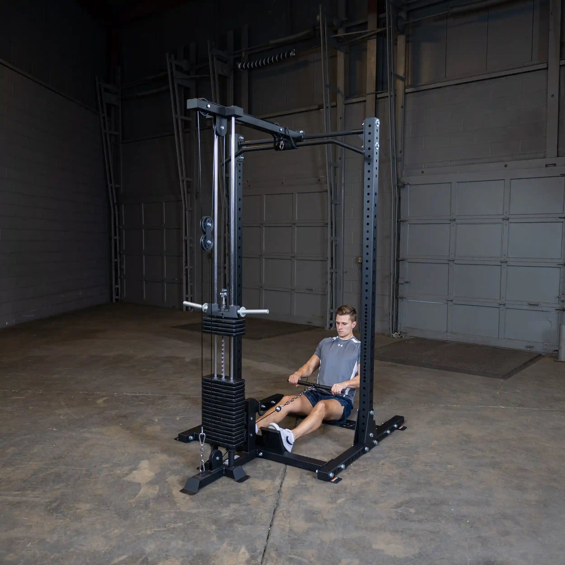 A person using the Body-Solid Pro ClubLine Lat Attachment SPRHLA for a seated rowing exercise in a spacious gym environment.