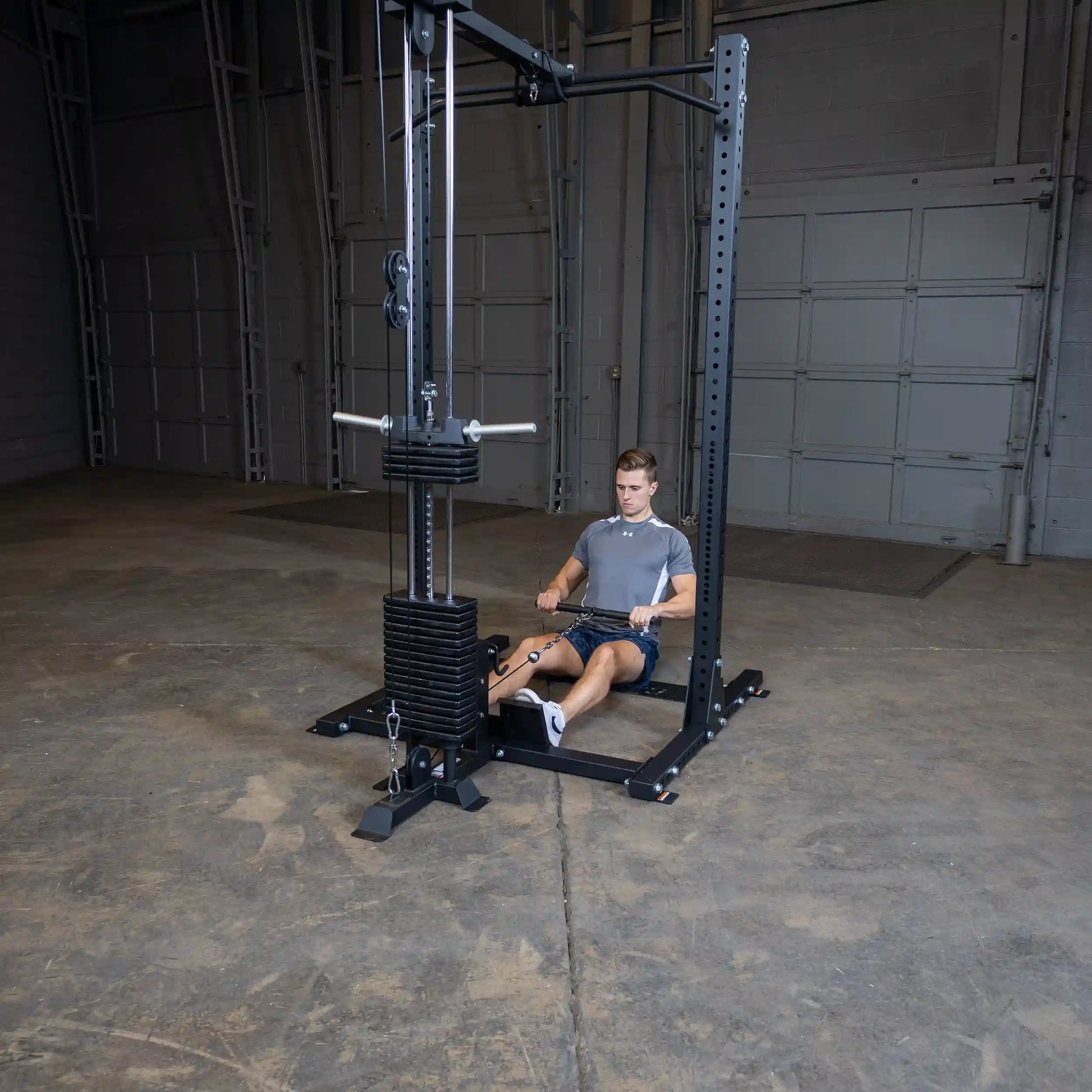 A person using the Body-Solid Pro ClubLine Lat Attachment SPRHLA in a gym setting, performing a seated row exercise with a weight stack in the background.