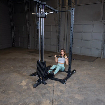 A woman performing a seated row exercise using the Body-Solid Pro ClubLine Lat Attachment SPRHLA in a spacious indoor gym setting.