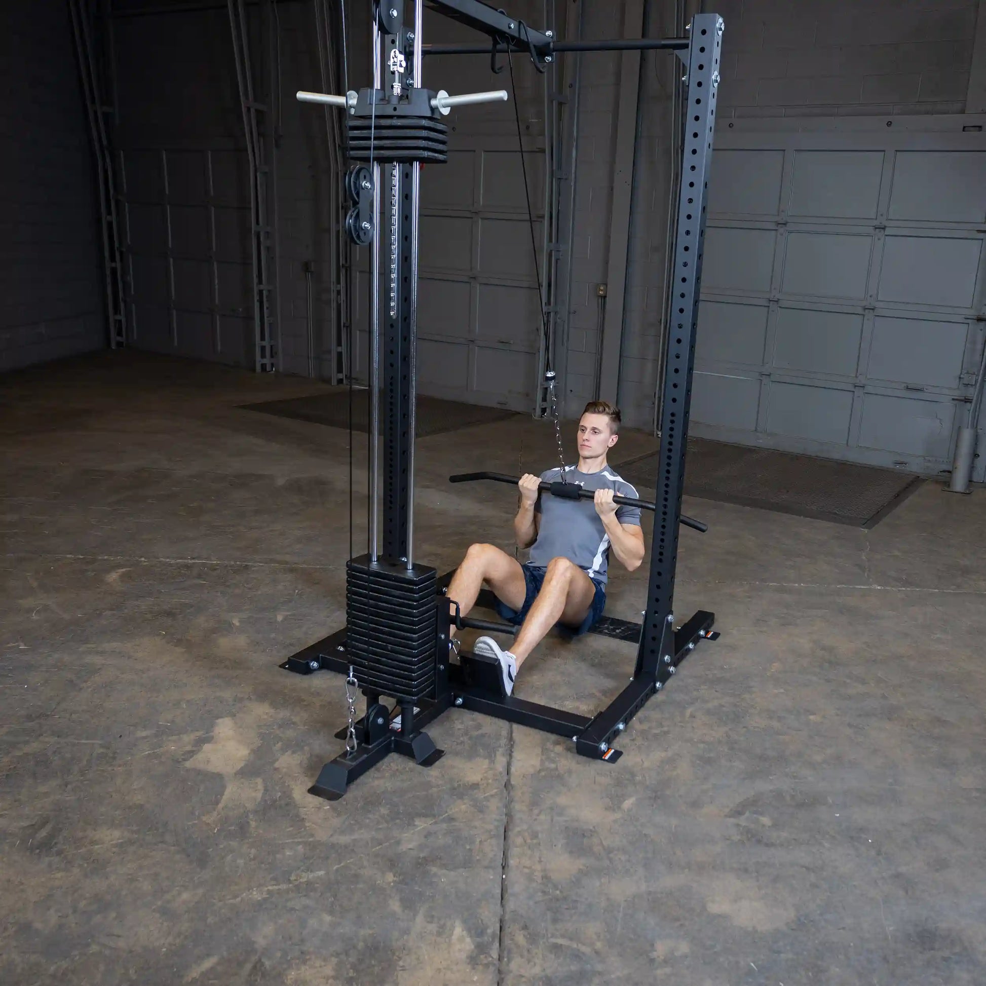 A person using the Body-Solid Pro ClubLine Lat Attachment SPRHLA in a gym setting, performing a seated lat pulldown exercise on a weight machine.