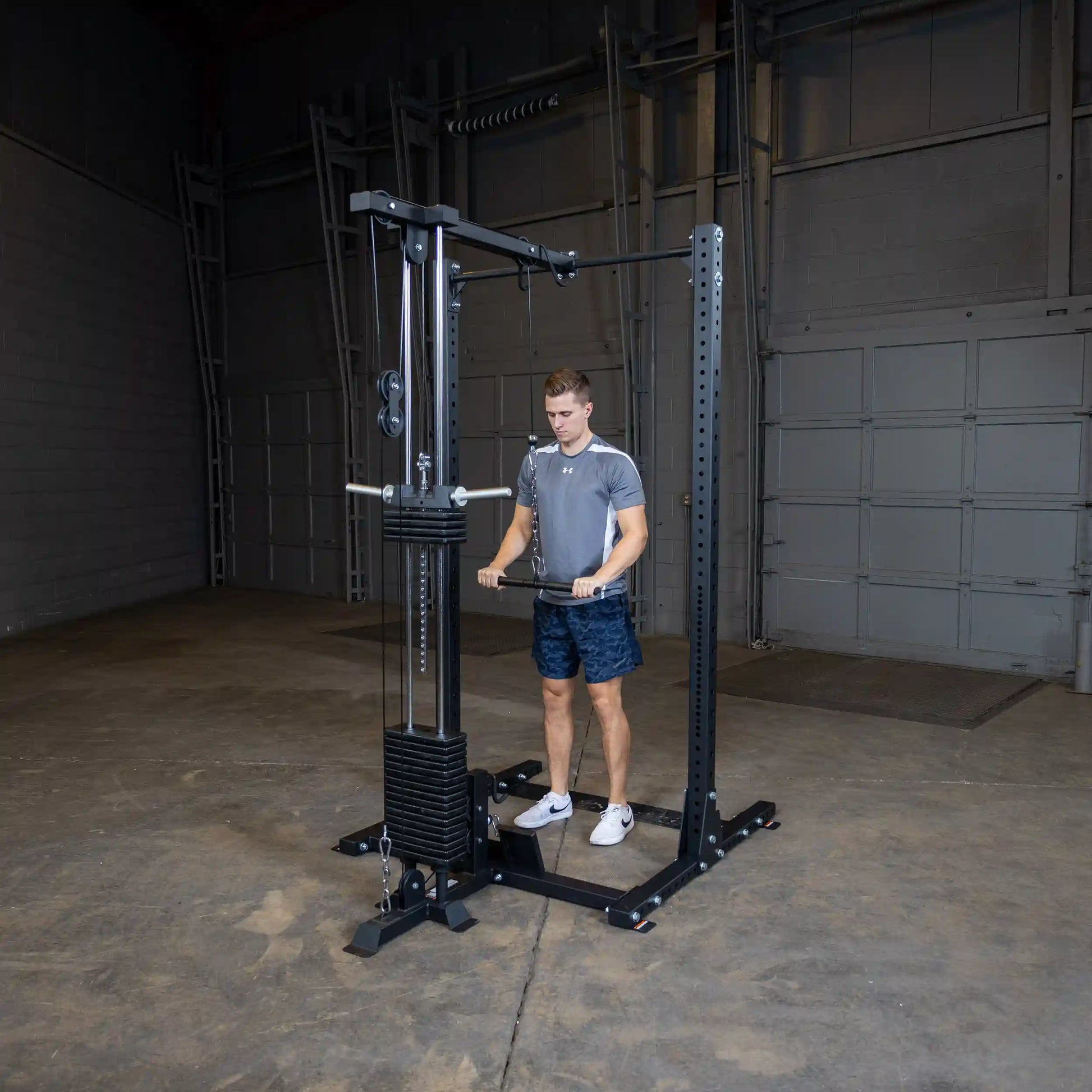 A person using the Body-Solid Pro ClubLine Lat Attachment SPRHLA in a gym setting, focusing on strength training with the lat pull-down machine.