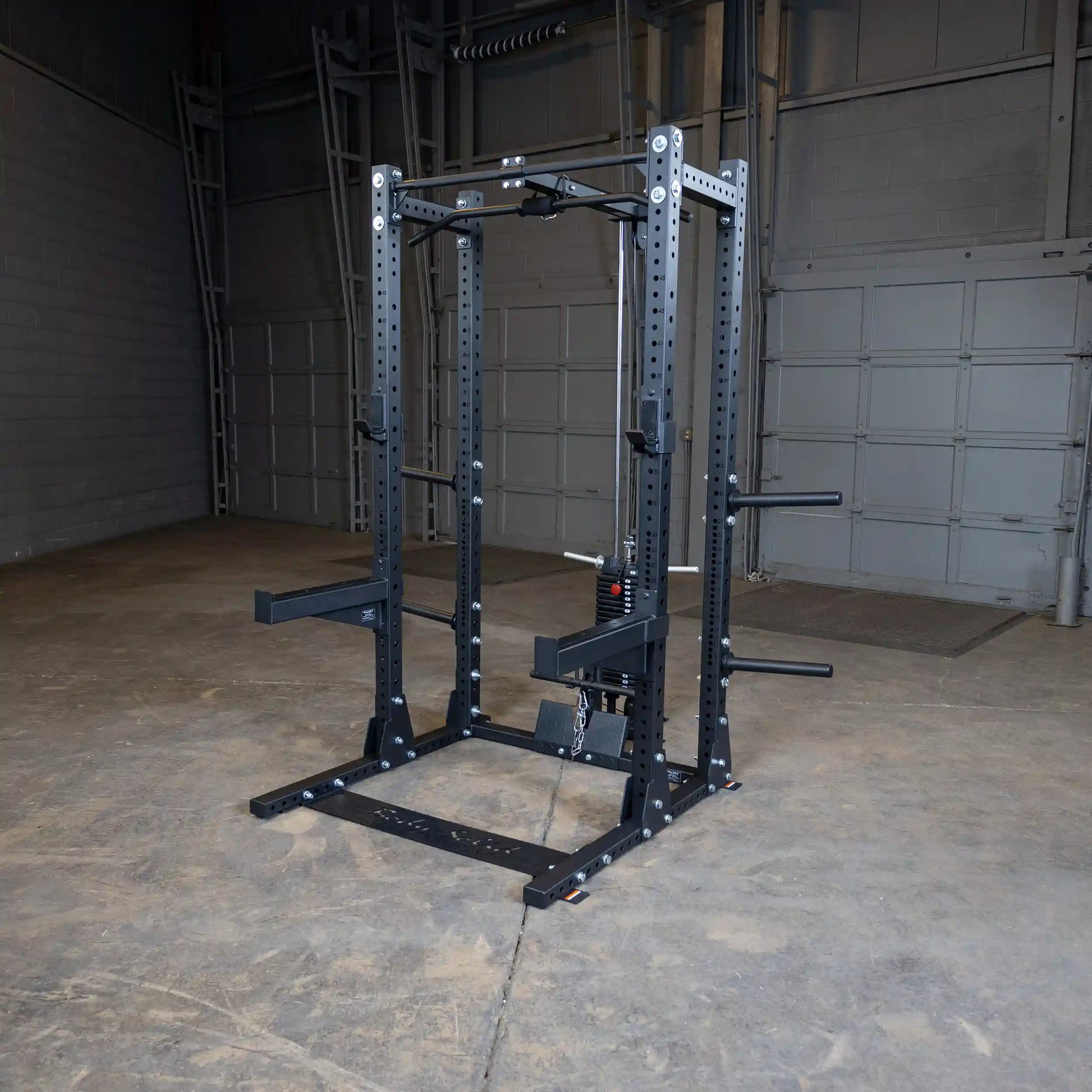 Image of a Body-Solid Pro ClubLine Lat Attachment SPRHLA mounted on a squat rack in an industrial gym setting with a concrete floor and gray walls.