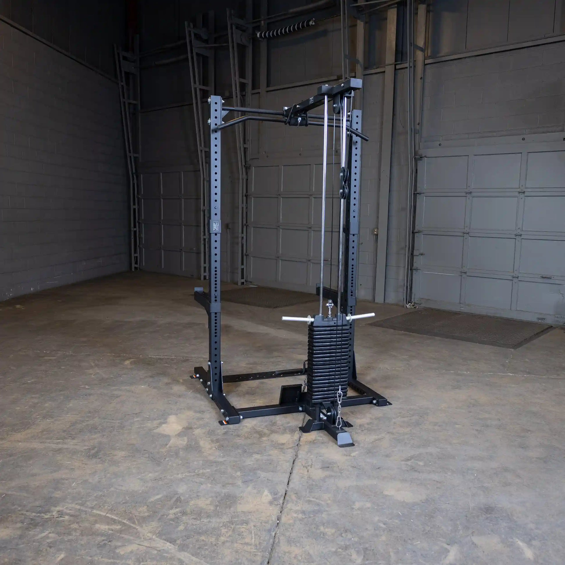 Image of the Body-Solid Pro ClubLine Lat Attachment SPRHLA, showcasing a black weightlifting machine positioned in a spacious, empty gym with concrete flooring and gray walls.