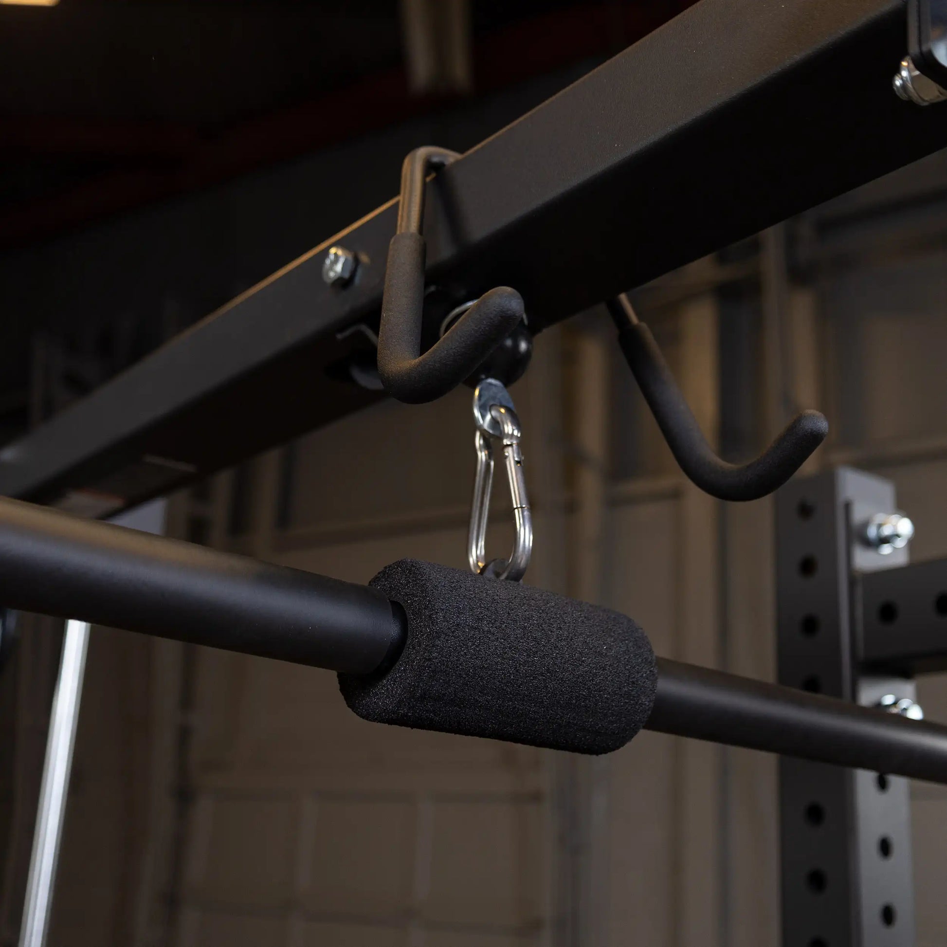 Close-up of the Body-Solid Pro ClubLine Lat Attachment SPRHLA featuring a black padded handle and metal carabiner, mounted on a sturdy frame.