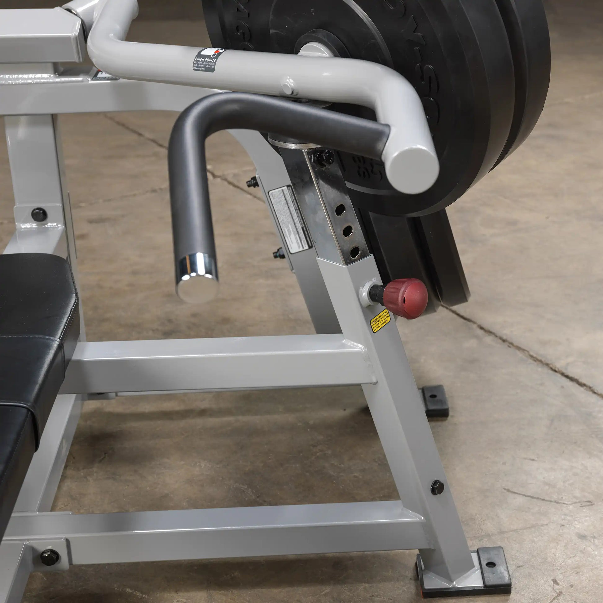 Close-up view of the Body-Solid Pro ClubLine Leverage Bench Press LVBP, showcasing the handle, weight plate, and adjustment features on a gym floor.