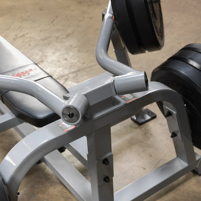 Close-up view of the Body-Solid Pro ClubLine Leverage Bench Press LVBP, showcasing the bench and weight plates in a gym setting.