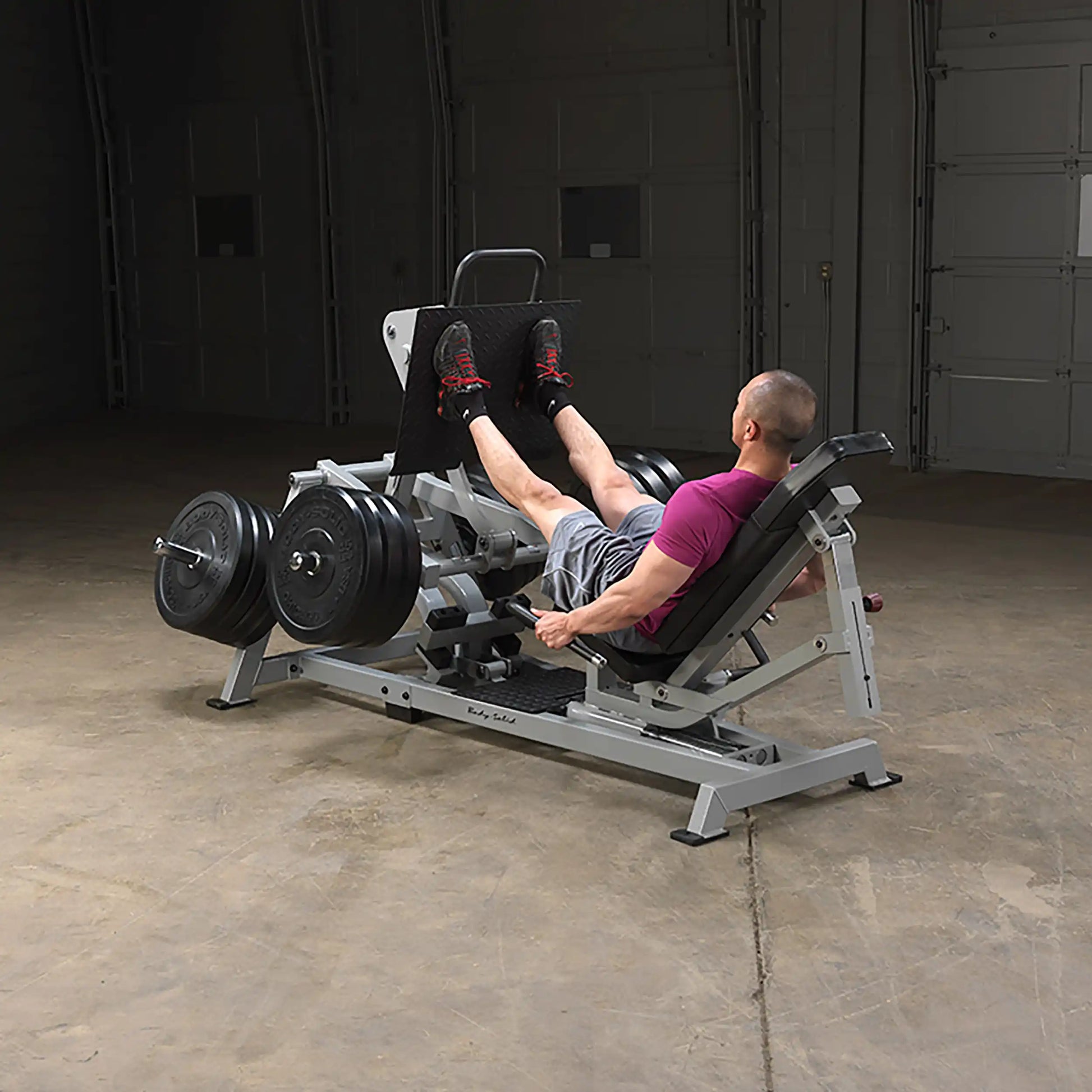 A person using the Body-Solid Pro ClubLine Leverage Horizontal Leg Press Machine LVLP in a gym setting, focusing on leg workouts with weights loaded on the machine.