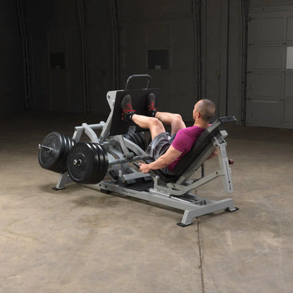A person using the Body-Solid Pro ClubLine Leverage Horizontal Leg Press Machine LVLP in a gym setting, performing leg presses with weights on the machine.