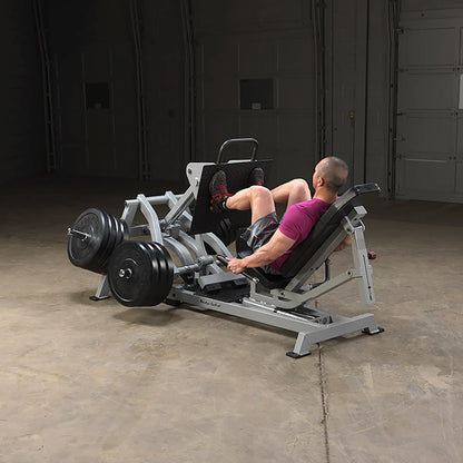 A person using the Body-Solid Pro ClubLine Leverage Horizontal Leg Press Machine LVLP in a gym setting, performing leg press exercises with weights.