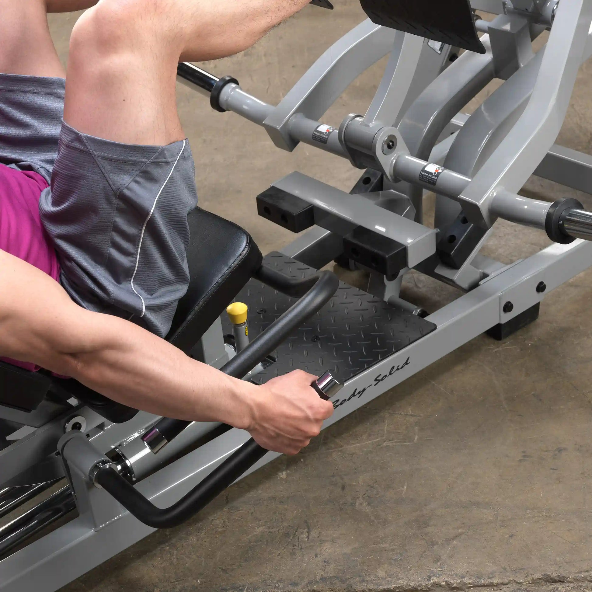 A person using the Body-Solid Pro ClubLine Leverage Horizontal Leg Press Machine LVLP, focusing on the leg press mechanism with their legs positioned on the platform and hands gripping the handles.