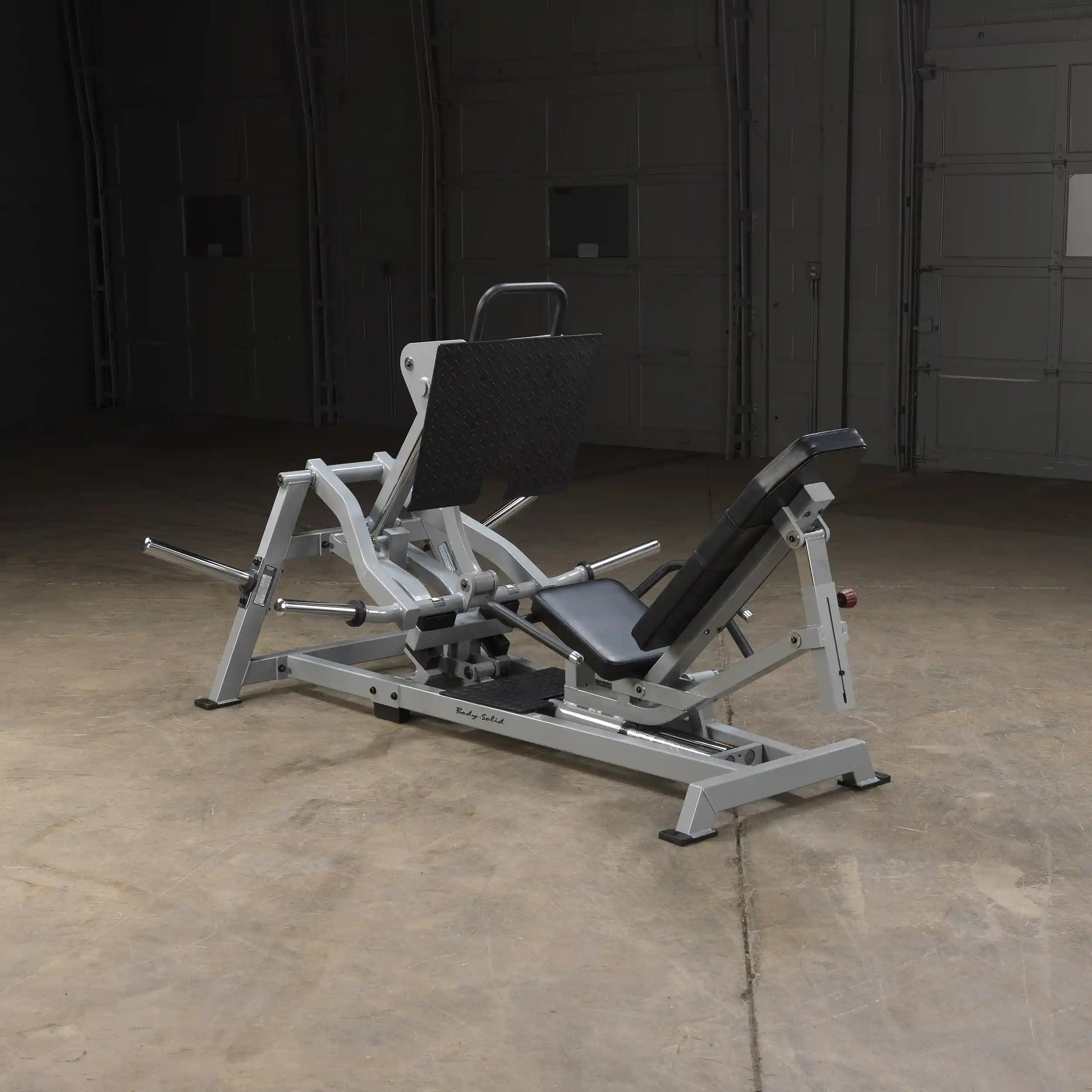 Body-Solid Pro ClubLine Leverage Horizontal Leg Press Machine LVLP positioned in a spacious gym environment with a concrete floor and dim lighting.
