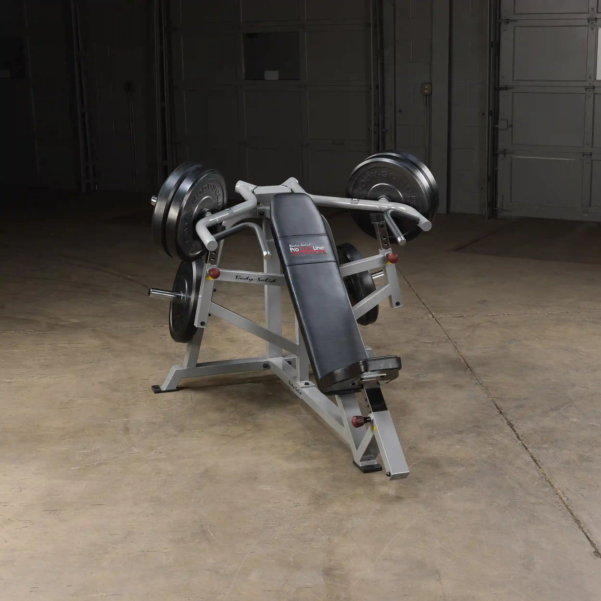 Body-Solid Pro ClubLine Leverage Incline Press LVIP, a weightlifting machine with a padded seat and adjustable arm supports, positioned in a well-lit gym space.