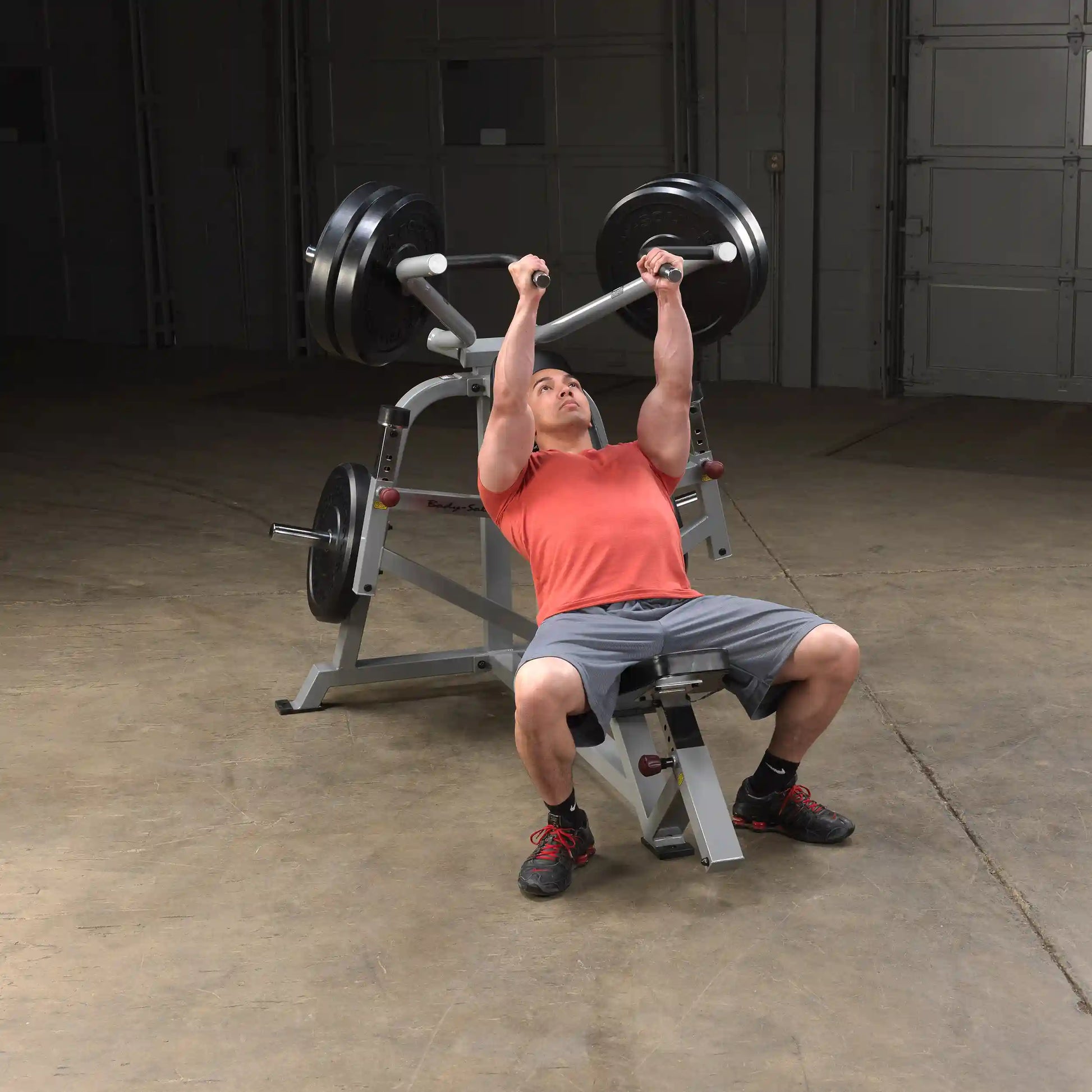 A man performing an incline press exercise on the Body-Solid Pro ClubLine Leverage Incline Press LVIP, lifting weights with focused determination in a gym setting.