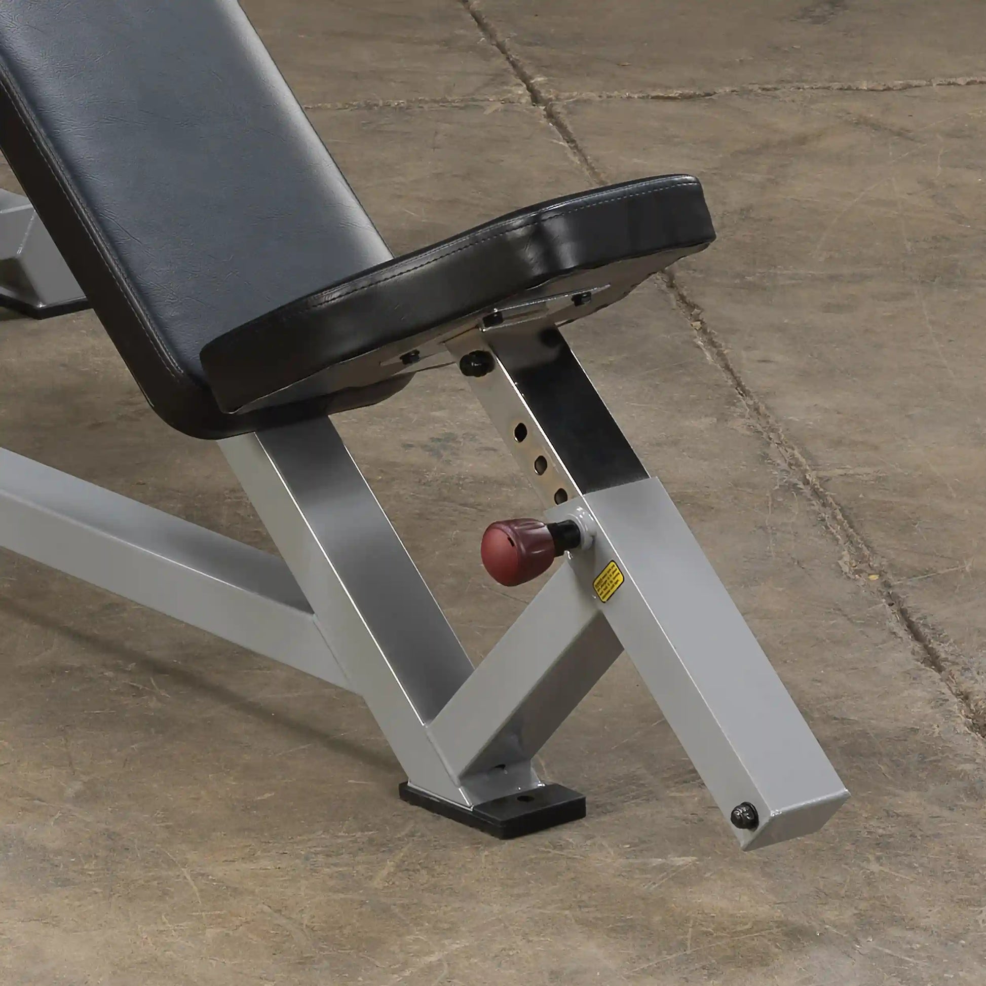 Close-up view of the adjustment mechanism and padded seat of the Body-Solid Pro ClubLine Leverage Incline Press LVIP, set against a textured floor surface.