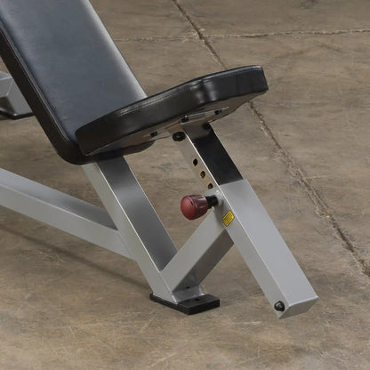 Close-up view of the adjustment mechanism and padded seat of the Body-Solid Pro ClubLine Leverage Incline Press LVIP, set against a textured floor surface.