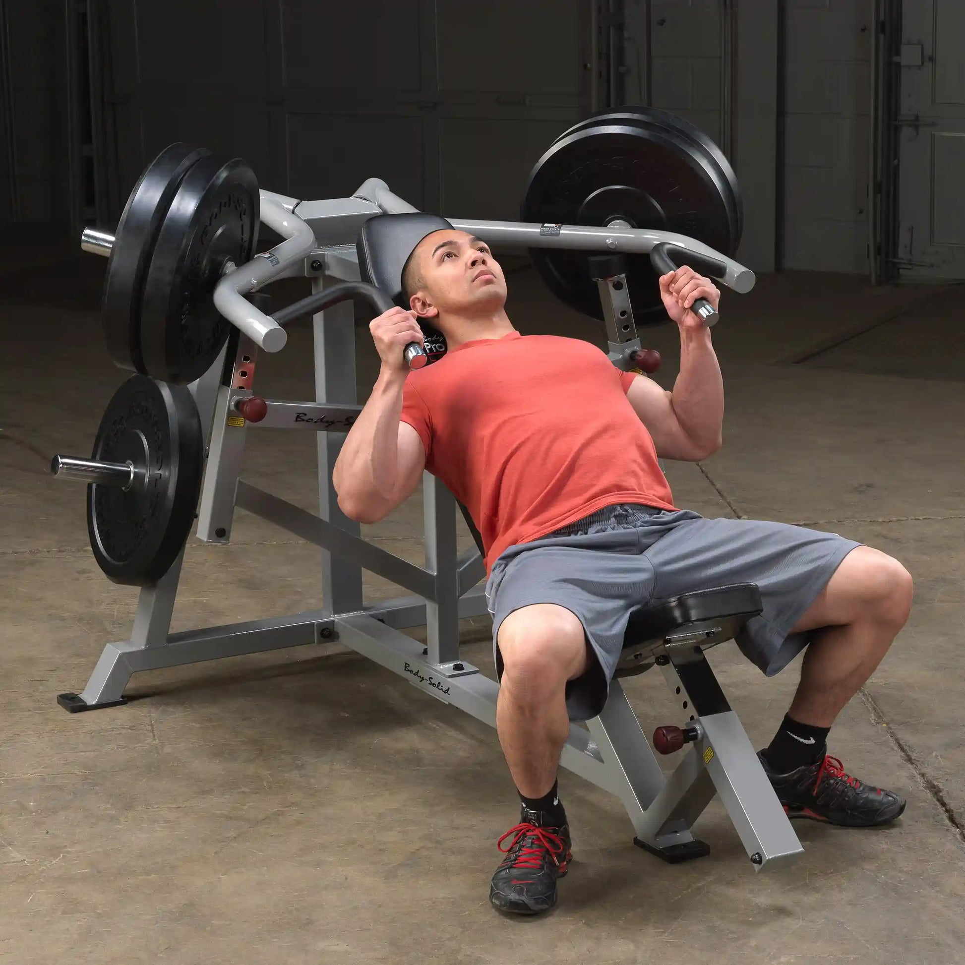A man performing an incline press on the Body-Solid Pro ClubLine Leverage Incline Press LVIP, with weights on the bar and seated on an adjustable bench.