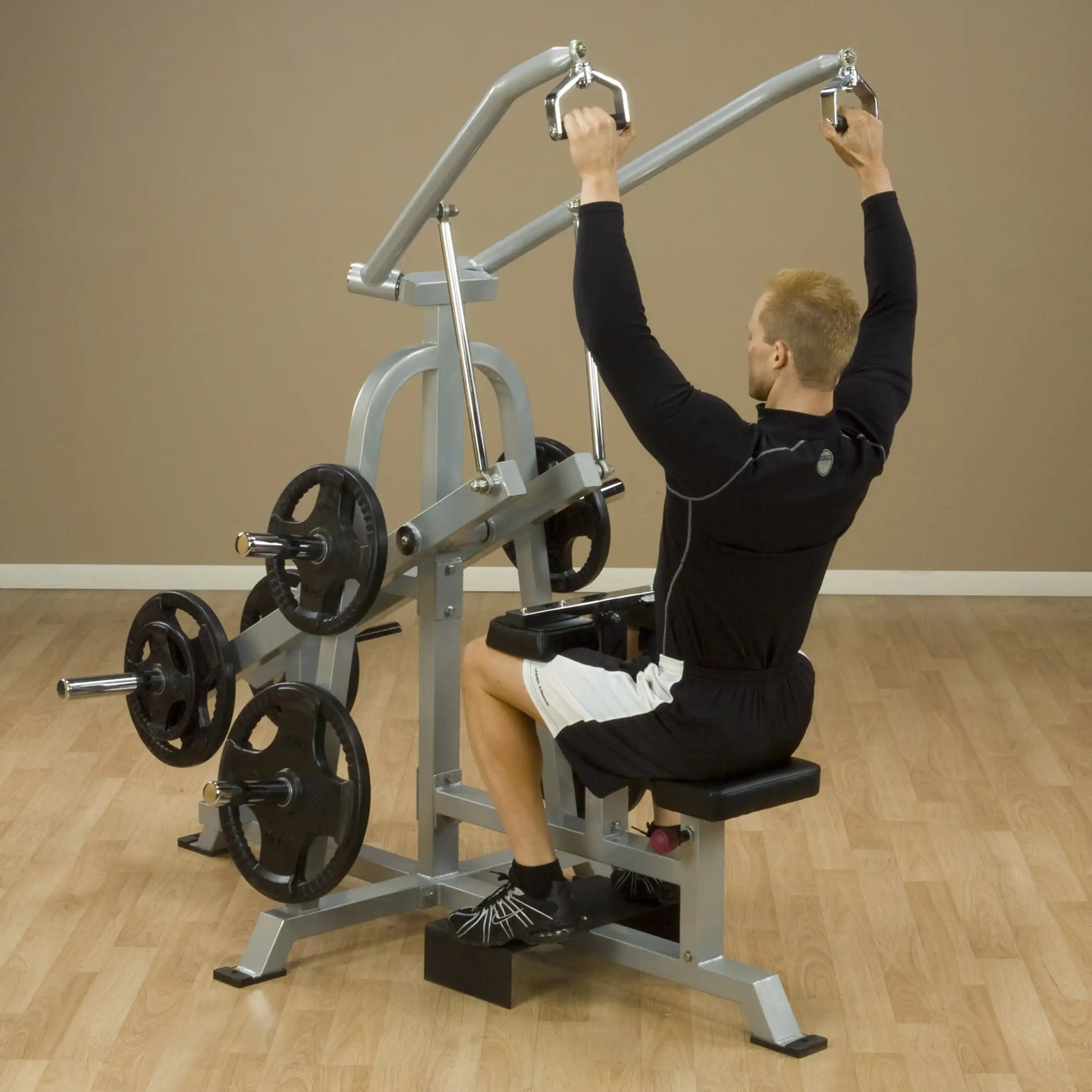 A person using the Body-Solid Pro ClubLine Leverage Lat Pulldown Machine LVLA, performing a lat pulldown exercise in a fitness studio.