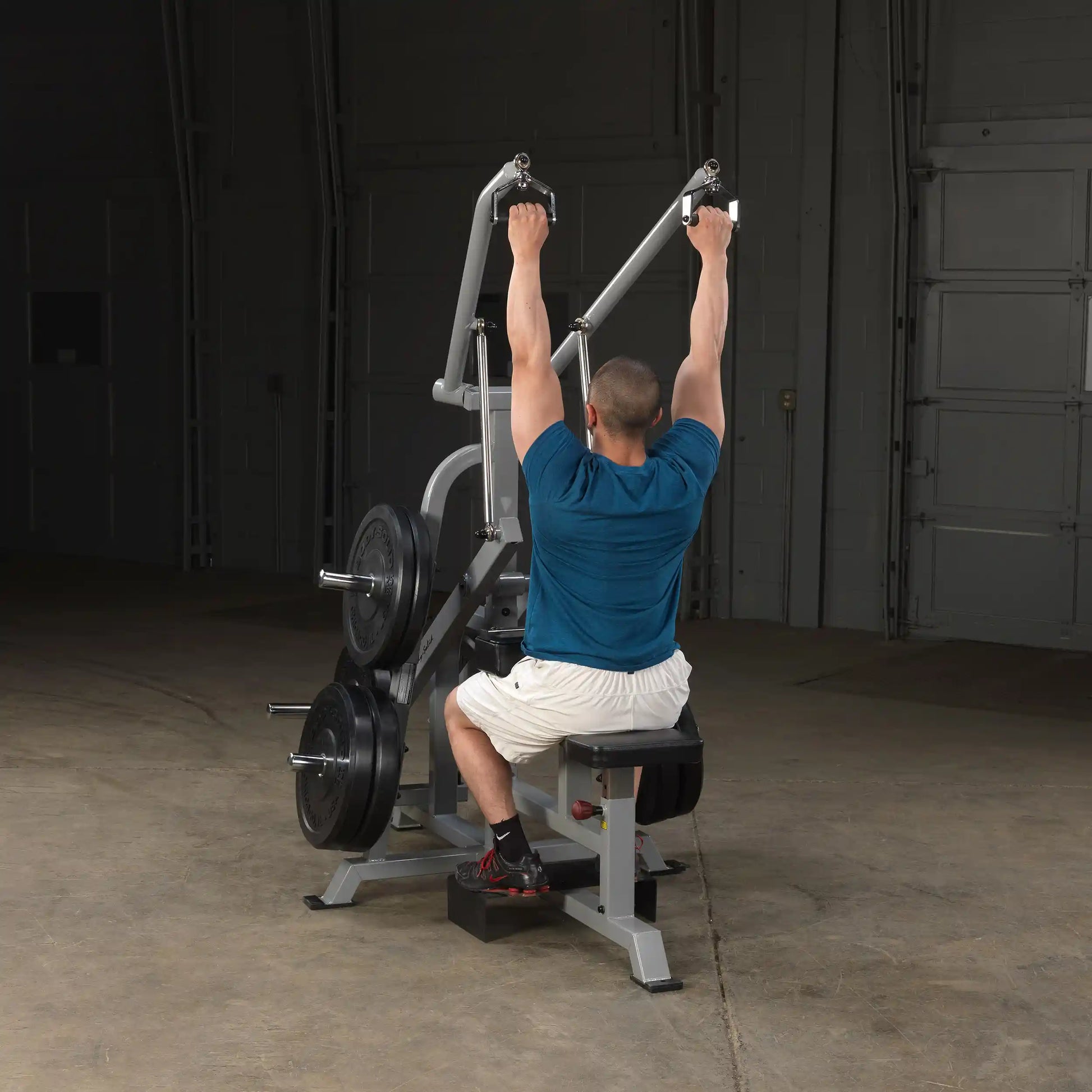 A person using the Body-Solid Pro ClubLine Leverage Lat Pulldown Machine LVLA in a gym setting, performing a lat pulldown exercise.