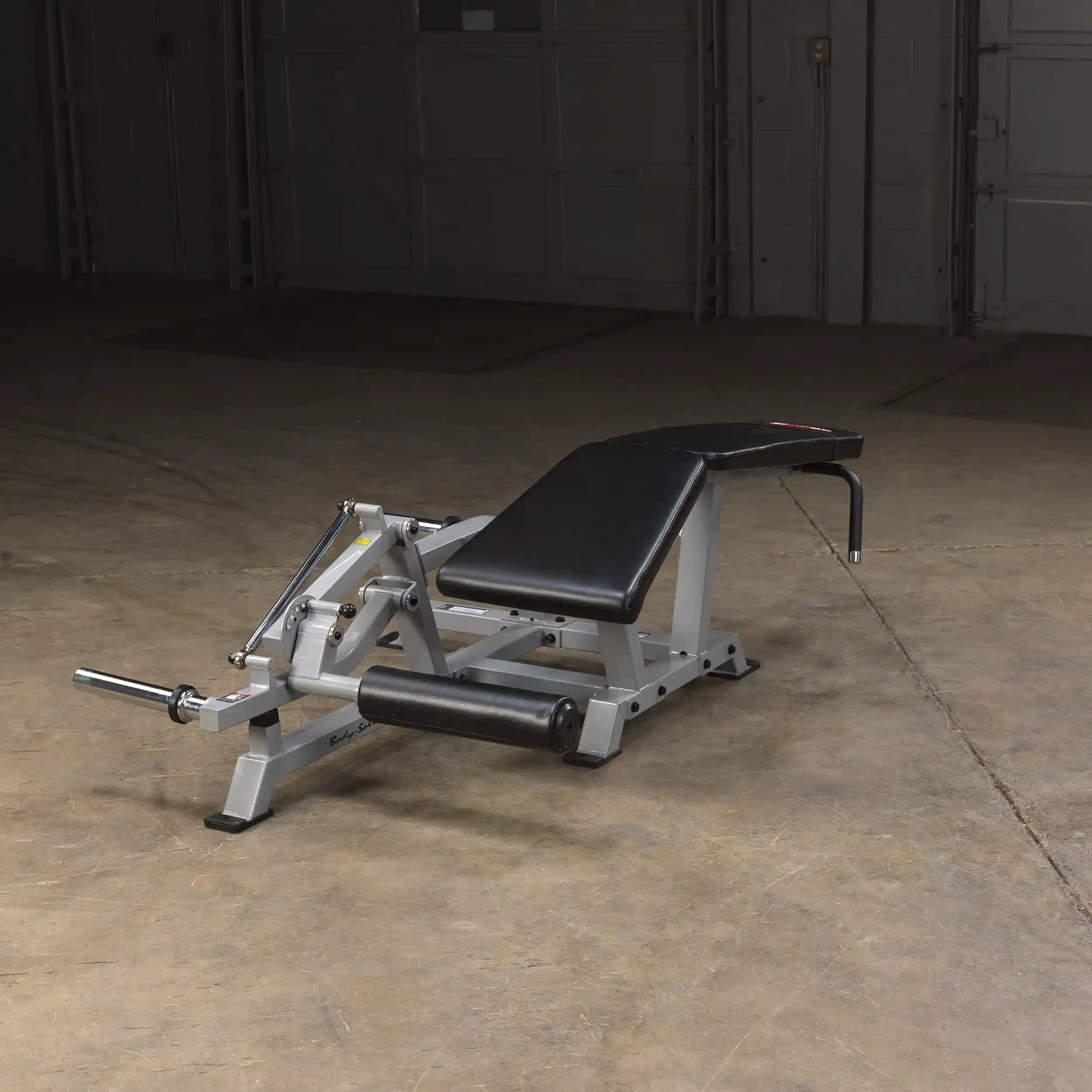 Body-Solid Pro ClubLine Leverage Leg Curl Machine LVLC positioned on a gym floor, featuring a padded black seat and leg support.