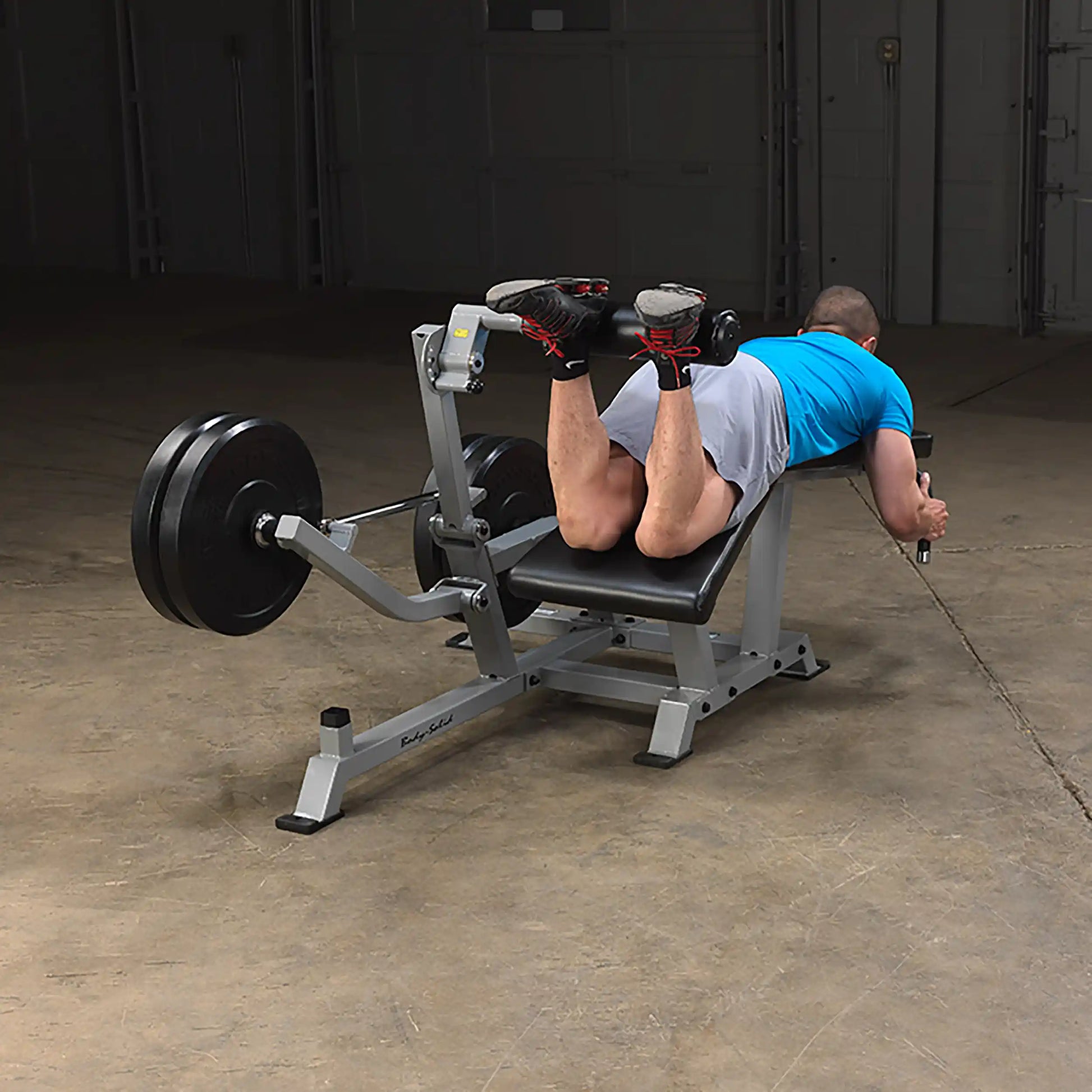 Person using the Body-Solid Pro ClubLine Leverage Leg Curl Machine LVLC in a gym setting, performing a leg curl exercise.