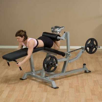 A woman demonstrating the Body-Solid Pro ClubLine Leverage Leg Curl Machine LVLC, performing leg curls in a fitness studio.