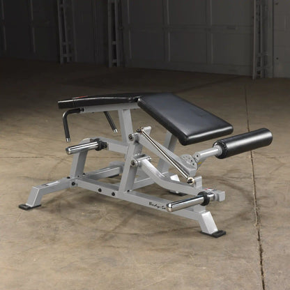 Body-Solid Pro ClubLine Leverage Leg Curl Machine LVLC positioned on a concrete floor, featuring a padded seat and adjustable leg rollers.