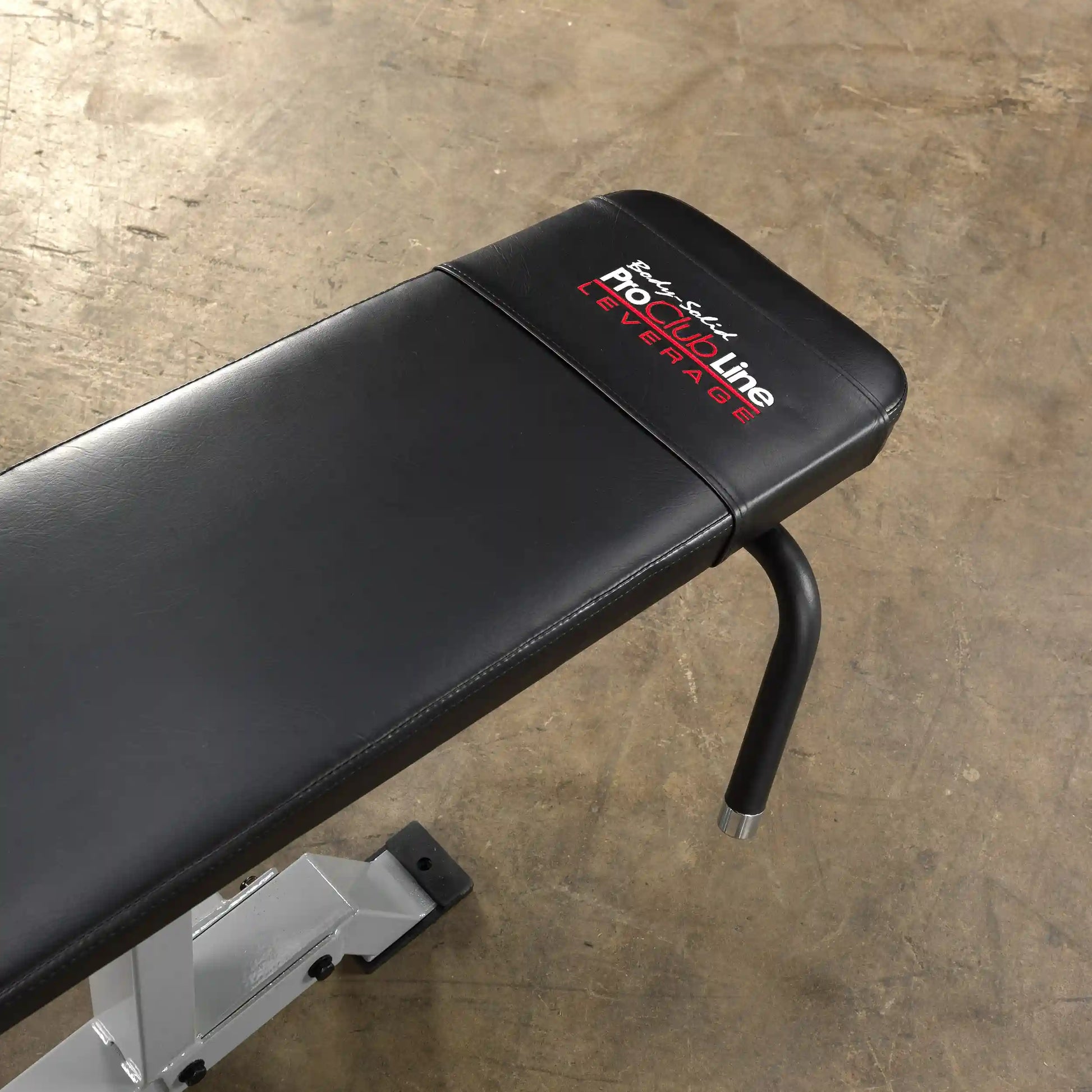 Close-up view of the padded seat of the Body-Solid Pro ClubLine Leverage Leg Curl Machine LVLC, showcasing its black leather finish and branding.