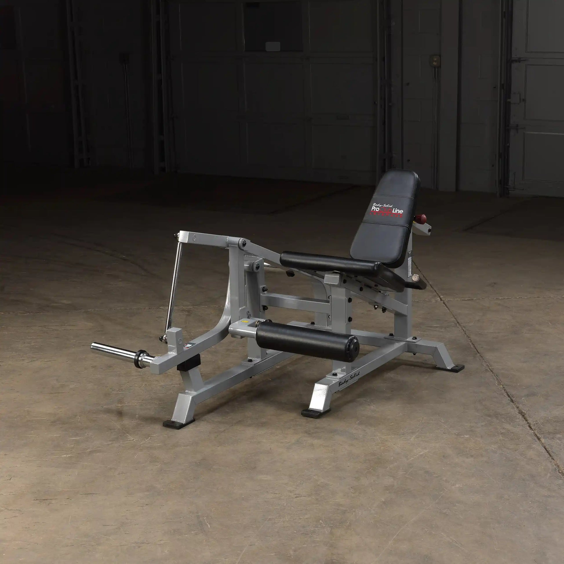 Body-Solid Pro ClubLine Leverage Leg Extension Machine LVLE positioned on a concrete floor in a dimly lit space.
