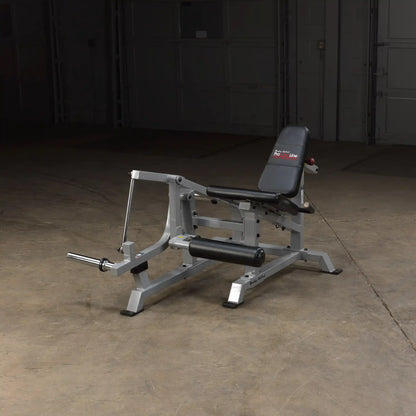 Body-Solid Pro ClubLine Leverage Leg Extension Machine LVLE positioned on a concrete floor in a dimly lit space.