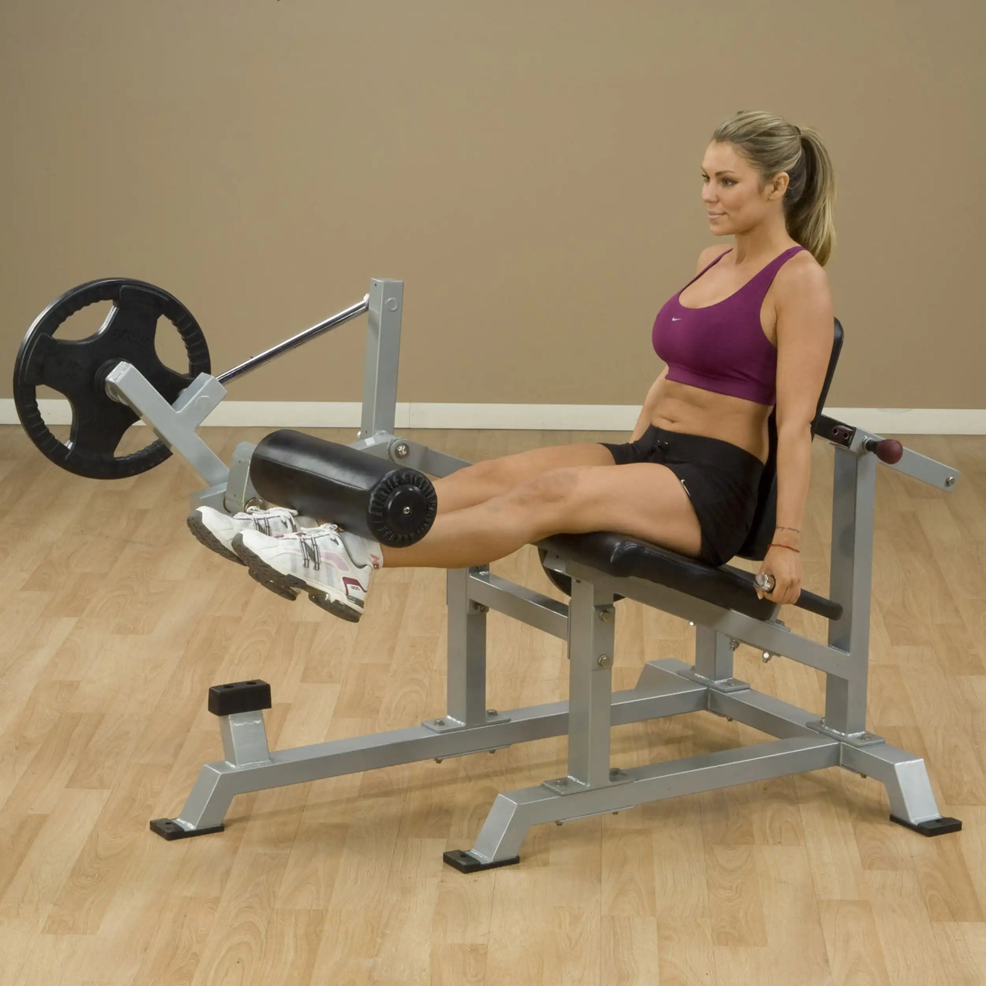 A woman using the Body-Solid Pro ClubLine Leverage Leg Extension Machine LVLE, demonstrating leg extension exercise in a fitness setting.