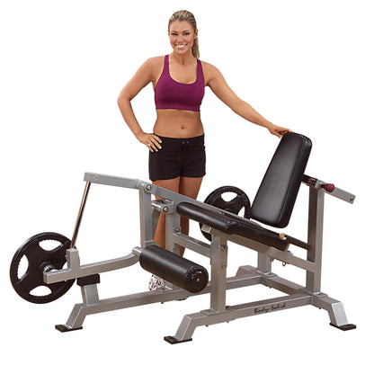 A woman standing next to the Body-Solid Pro ClubLine Leverage Leg Extension Machine LVLE, demonstrating its features.
