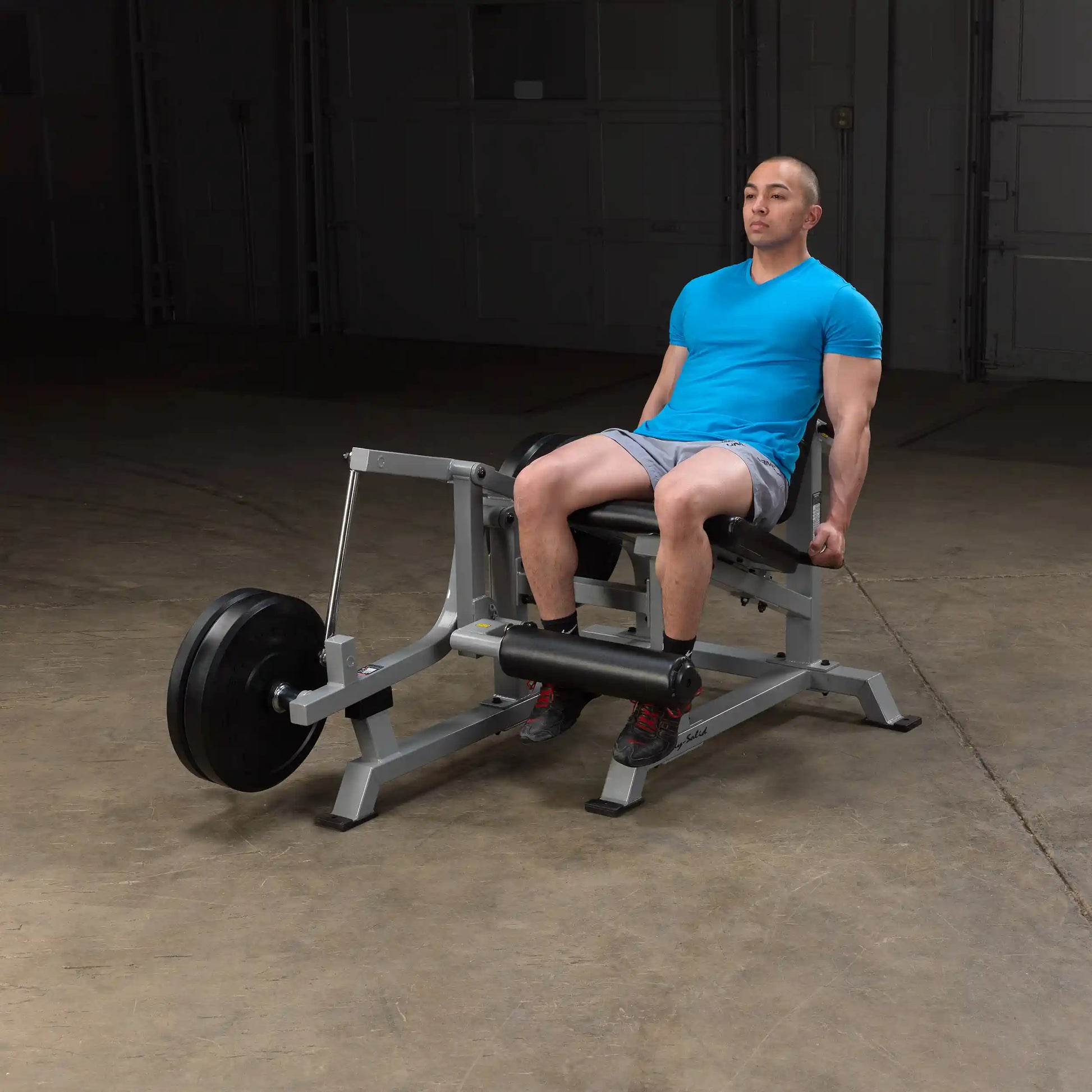 A person using the Body-Solid Pro ClubLine Leverage Leg Extension Machine LVLE in a gym setting, performing leg extensions.