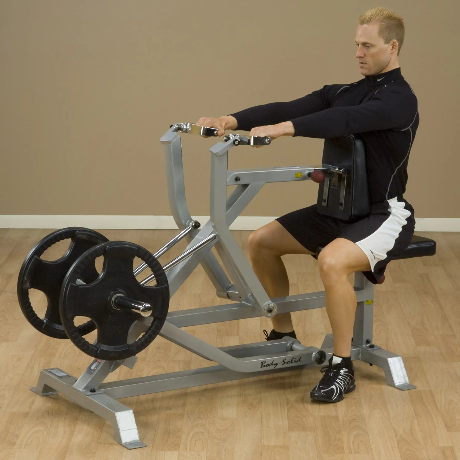 A person using the Body-Solid Pro ClubLine Leverage Seated Row Machine LVSR, demonstrating proper form while seated and pulling the handles towards them with weights on the machine.