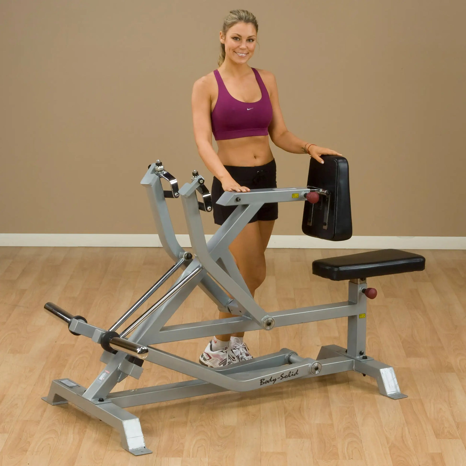 A fitness model demonstrating the Body-Solid Pro ClubLine Leverage Seated Row Machine LVSR, showcasing its adjustable seat and rowing handles in a gym setting.