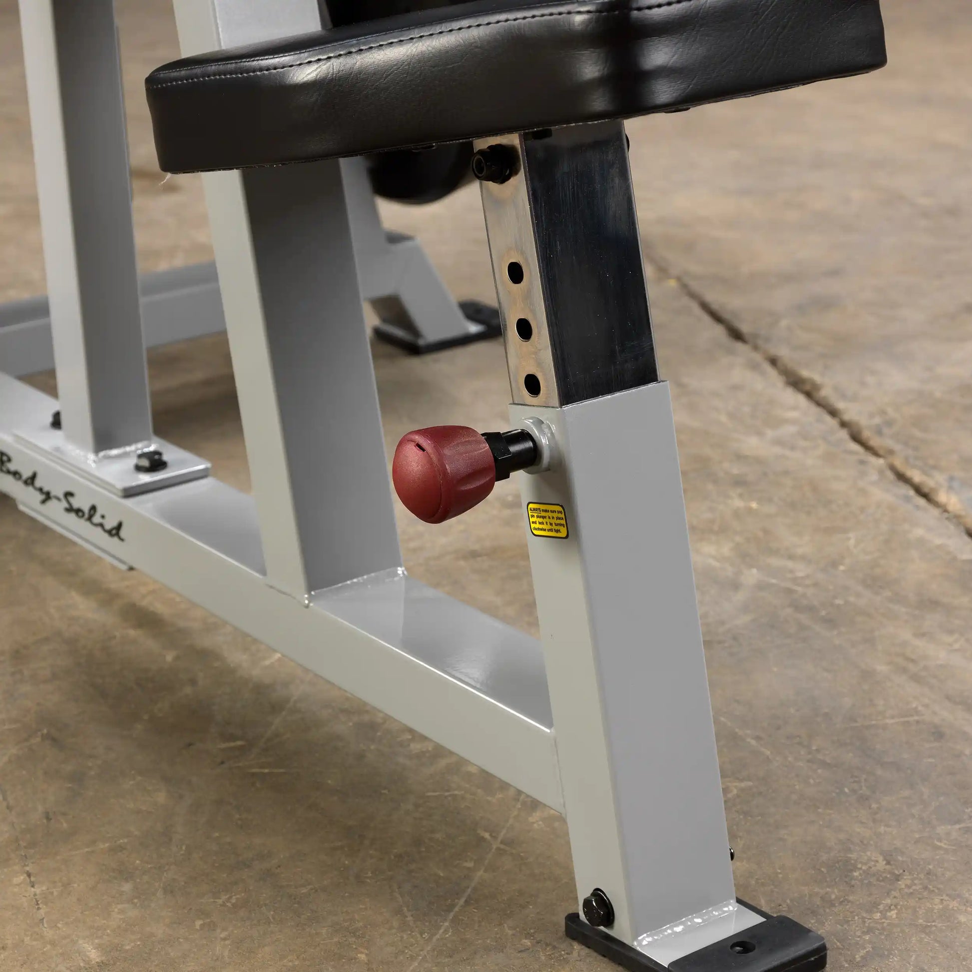 Close-up of the adjustment knob and frame of the Body-Solid Pro ClubLine Leverage Shoulder Press Machine LVSP, set on a textured floor.