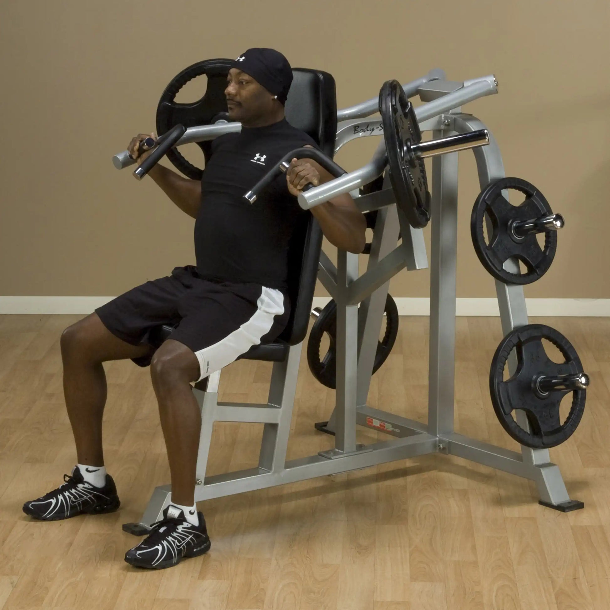 A person demonstrating the Body-Solid Pro ClubLine Leverage Shoulder Press Machine LVSP, seated and lifting weights in a fitness setting.