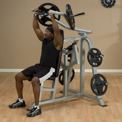 A person using the Body-Solid Pro ClubLine Leverage Shoulder Press Machine LVSP, performing an overhead press exercise in a fitness studio.