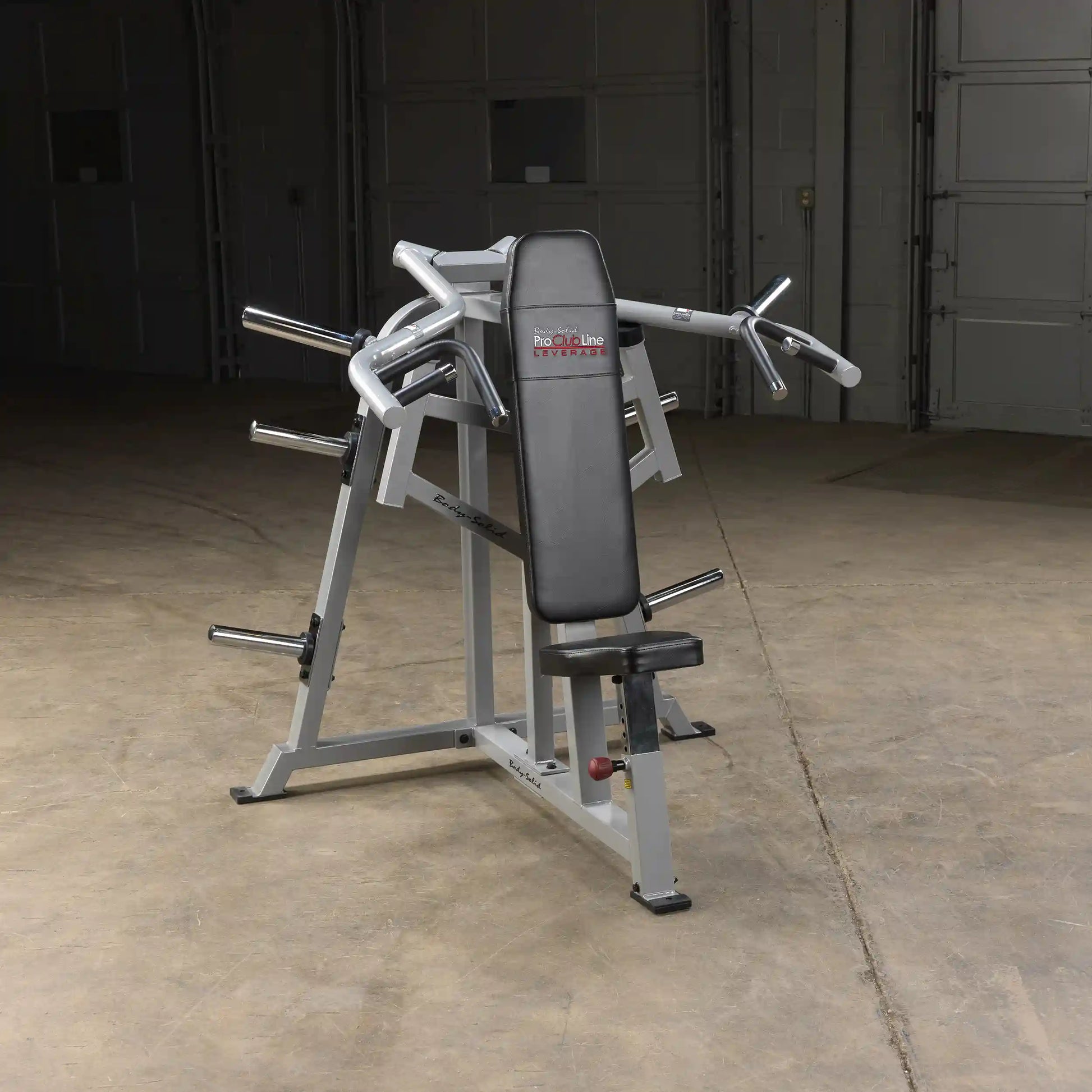Body-Solid Pro ClubLine Leverage Shoulder Press Machine LVSP positioned in a spacious gym setting with a concrete floor and garage-style background.