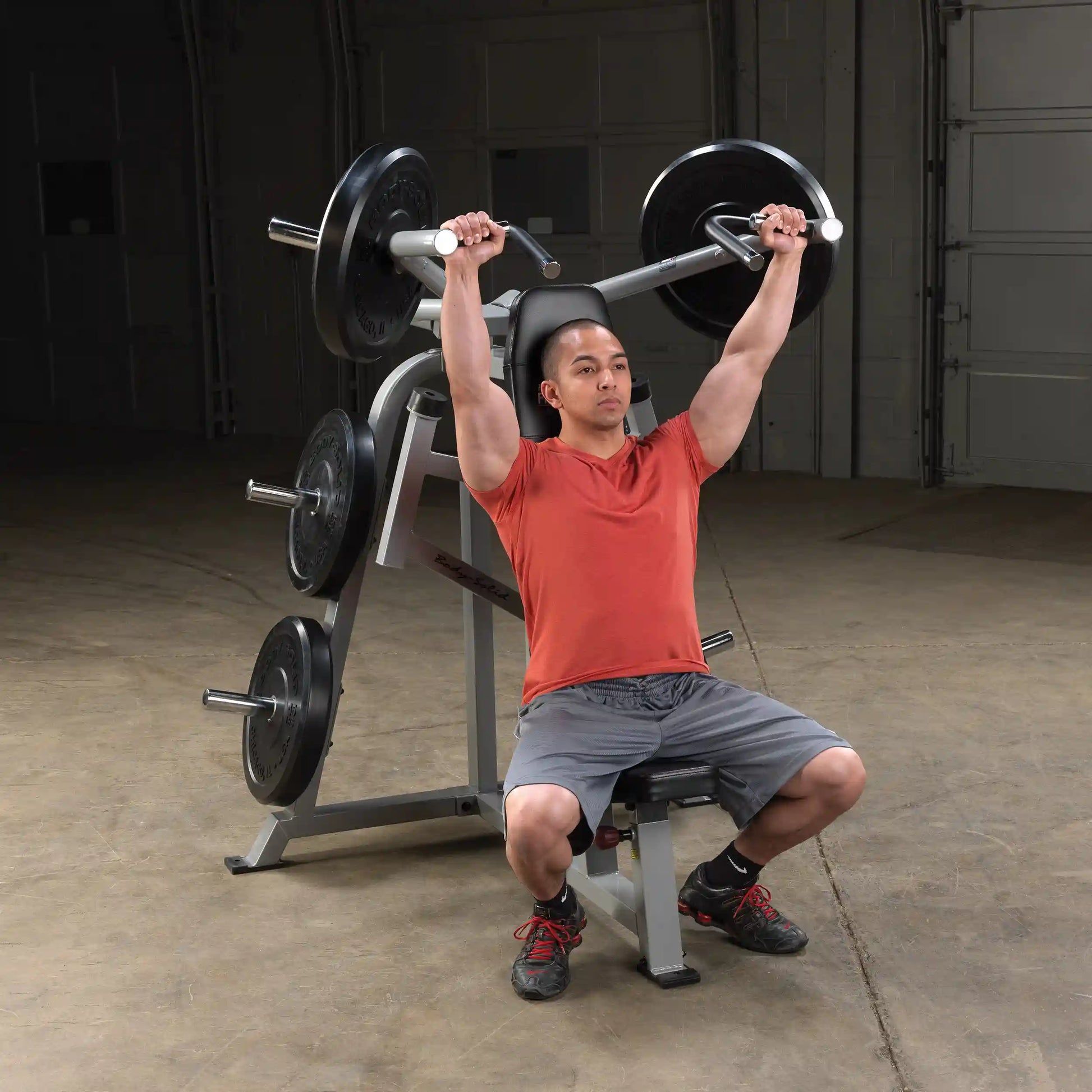 A person performing an exercise on the Body-Solid Pro ClubLine Leverage Shoulder Press Machine LVSP, lifting weights overhead while seated.