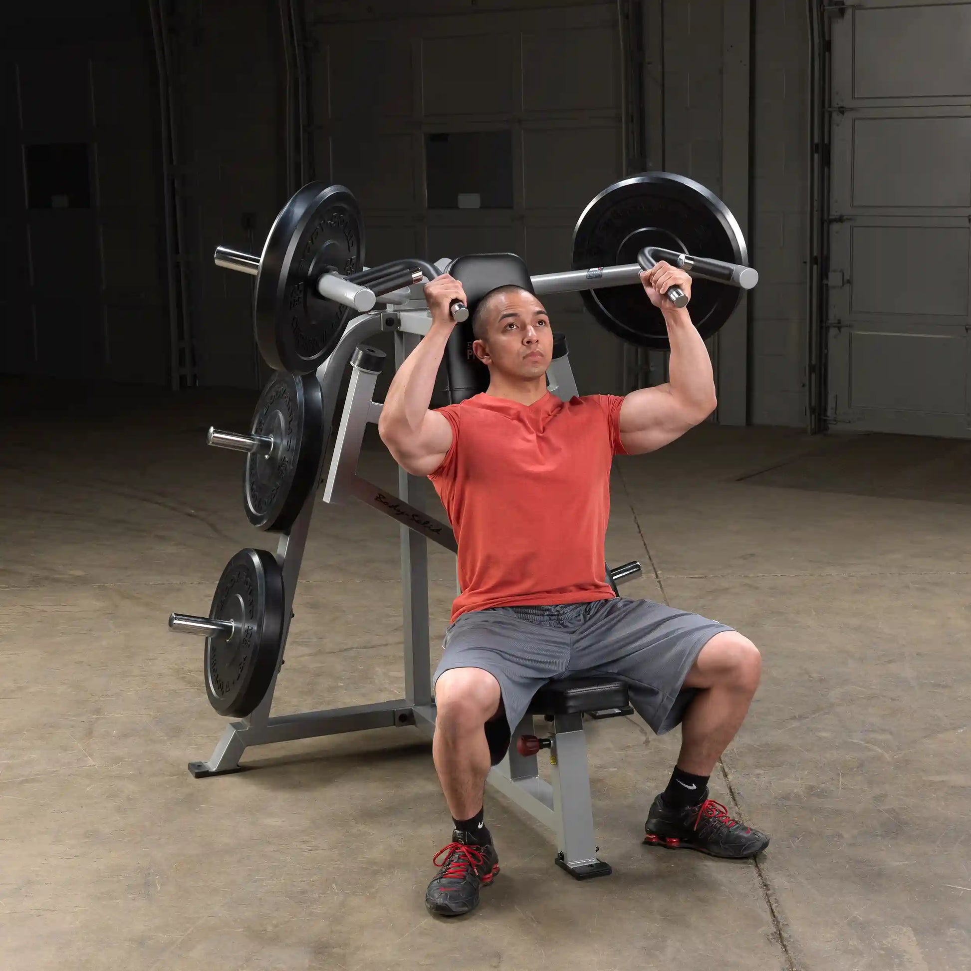 A person using the Body-Solid Pro ClubLine Leverage Shoulder Press Machine LVSP, performing a shoulder press exercise, in a gym setting.