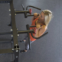A woman performing a chin-up using the Body-Solid Pro ClubLine Multi-Grip Chin Up Attachment SPRMGC in a gym setting, showcasing the equipment's multi-grip handles and sturdy design.