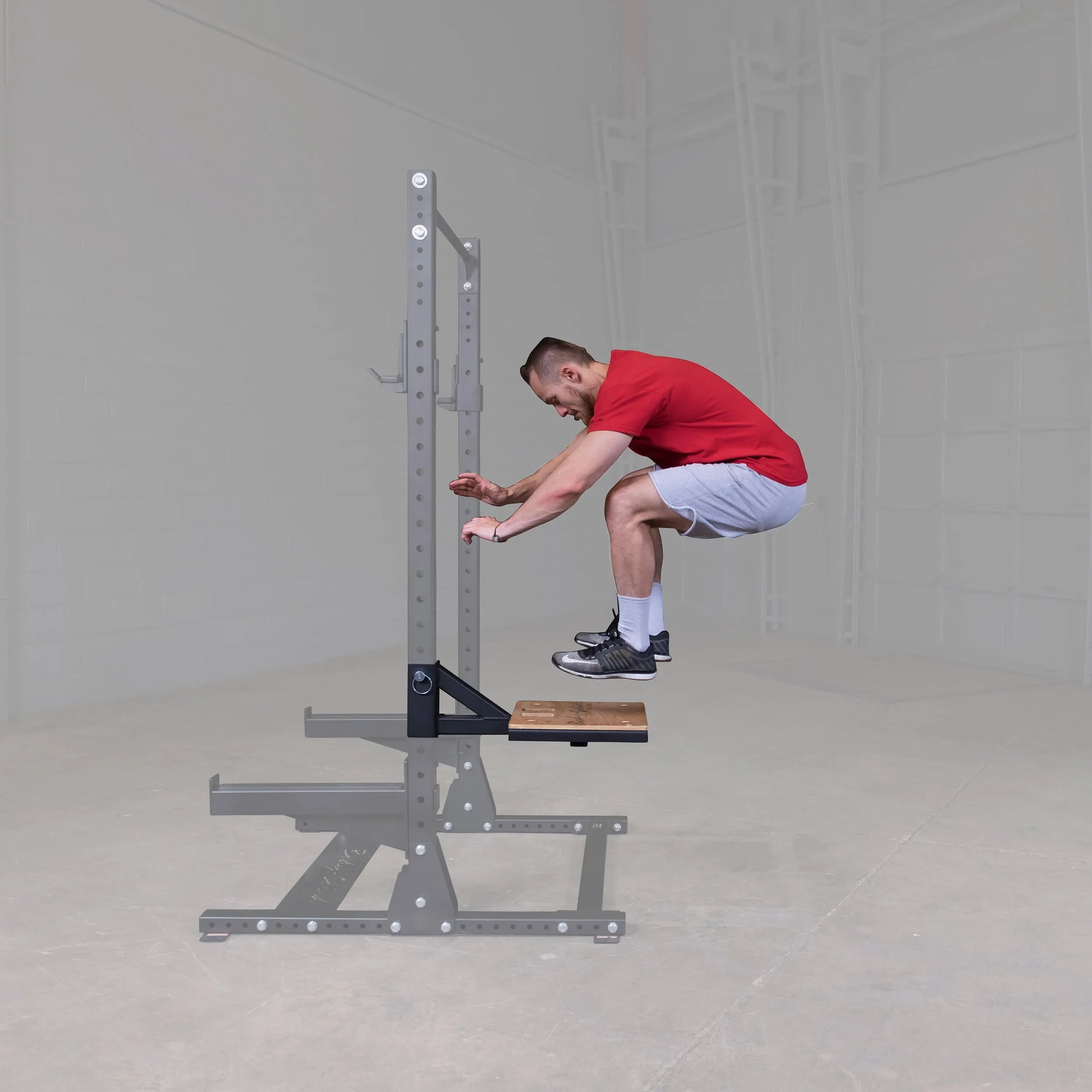 A person performing a jump exercise on the Body-Solid Pro ClubLine Plyo Step Attachment SPRSTEP, showcasing the equipment's use in a fitness setting.