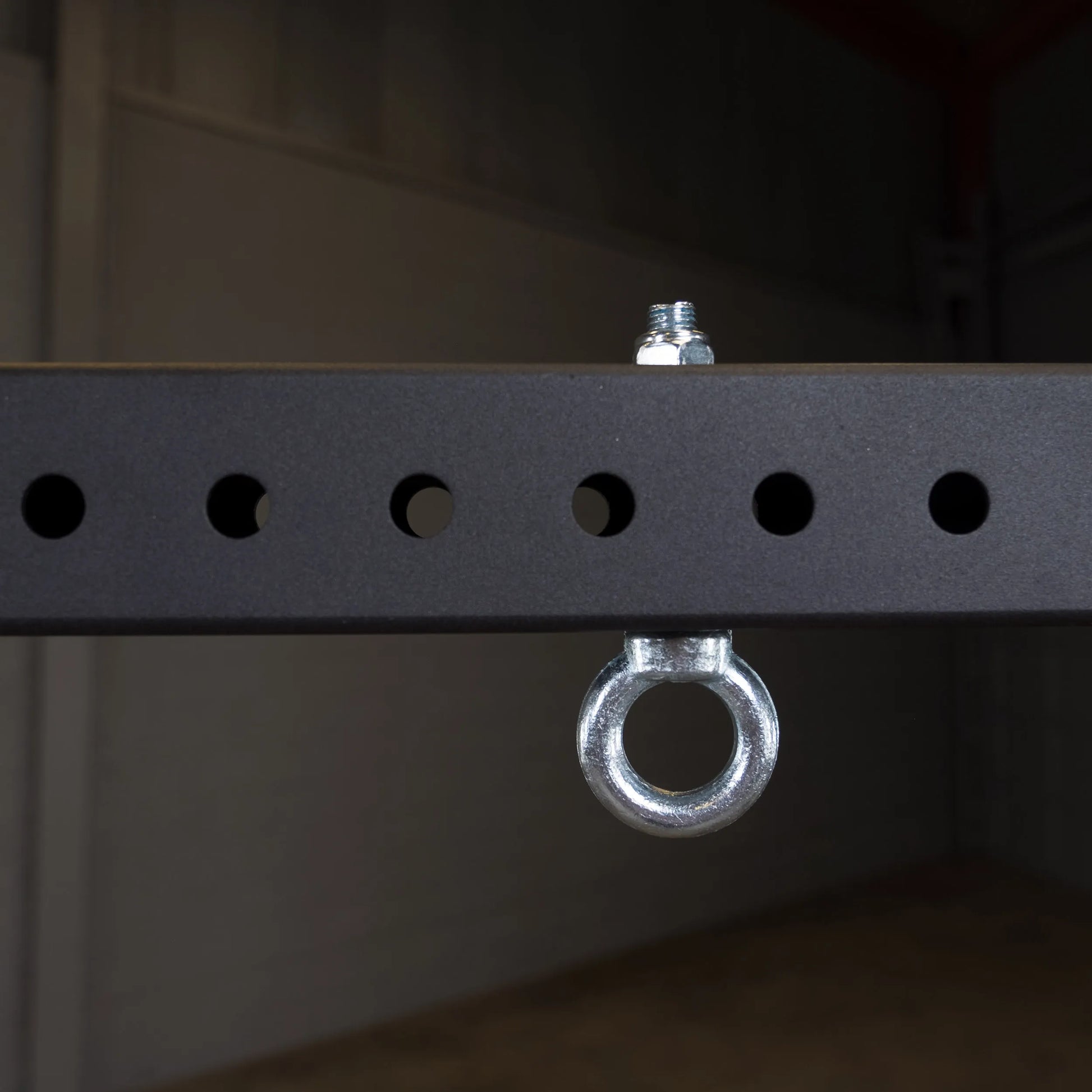 Close-up image of a metal connecting bar featuring evenly spaced round holes and an attached circular metal ring, part of the Body-Solid Pro ClubLine Power Rack Connecting Bar SPRACB.