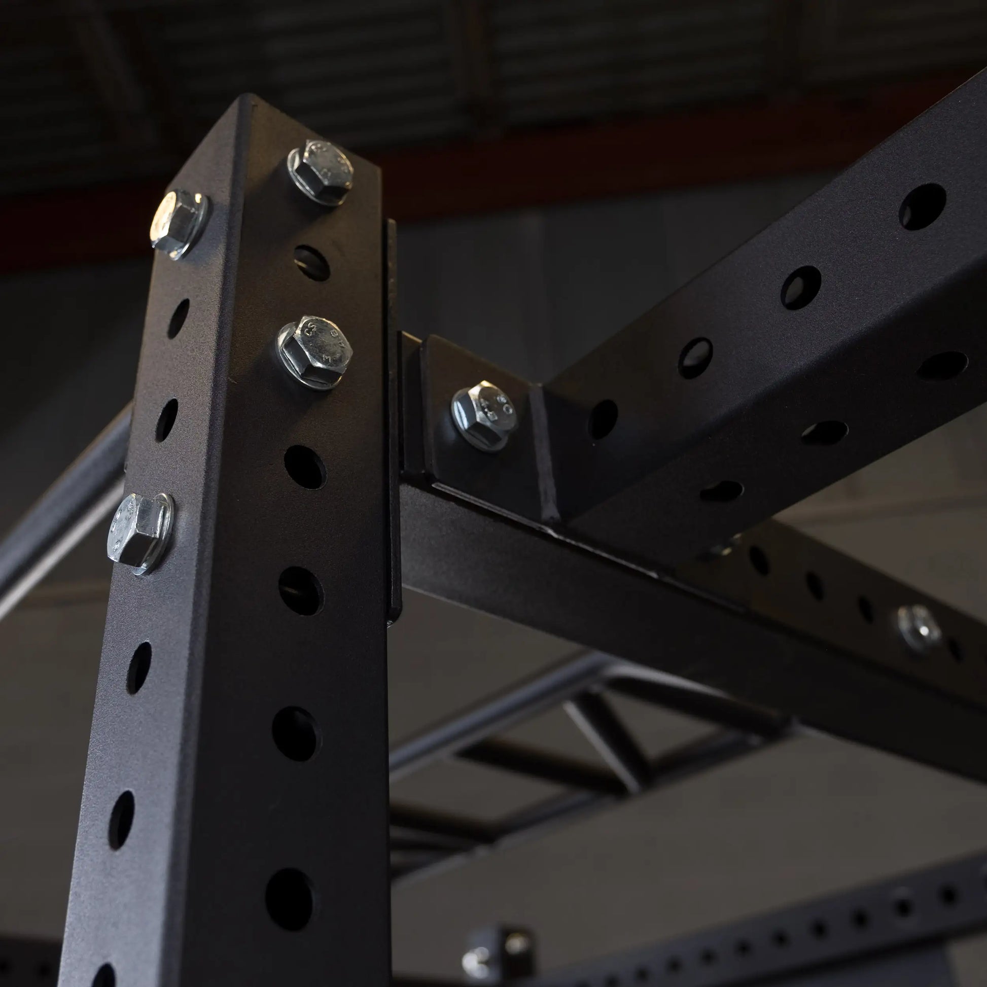 Close-up view of a Body-Solid Pro ClubLine Power Rack Connecting Bar SPRACB with bolts and perforated metal structure.